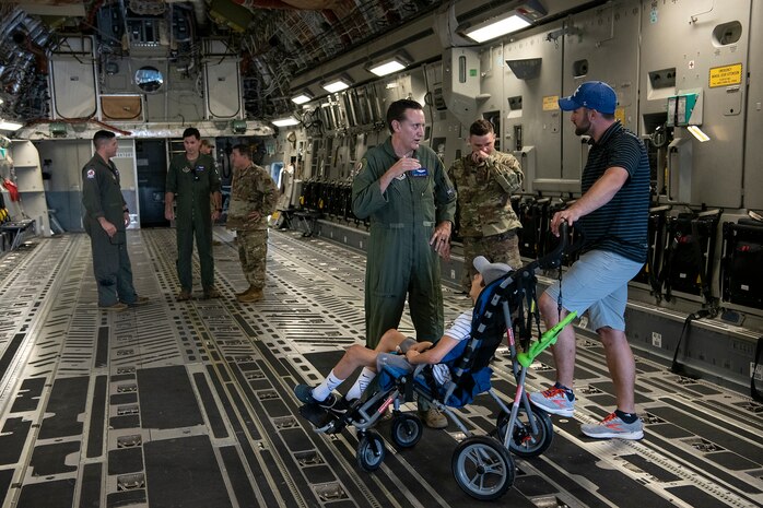 (From left) Master Sgt. James Ebert, 701st Airlift Squadron loadmaster, and Tech Sgt. Wade Griffith, 437th Maintenance Squadron, speak with Braiden and Matt Adkins while touring a C-17 Globemaster III at Joint Base Charleston, South Carolina July 14, 2021.