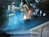 Vermont Air National Guard fire fighters work to extinguish a fire on the roof of a small apartment building in Winooski, VT.