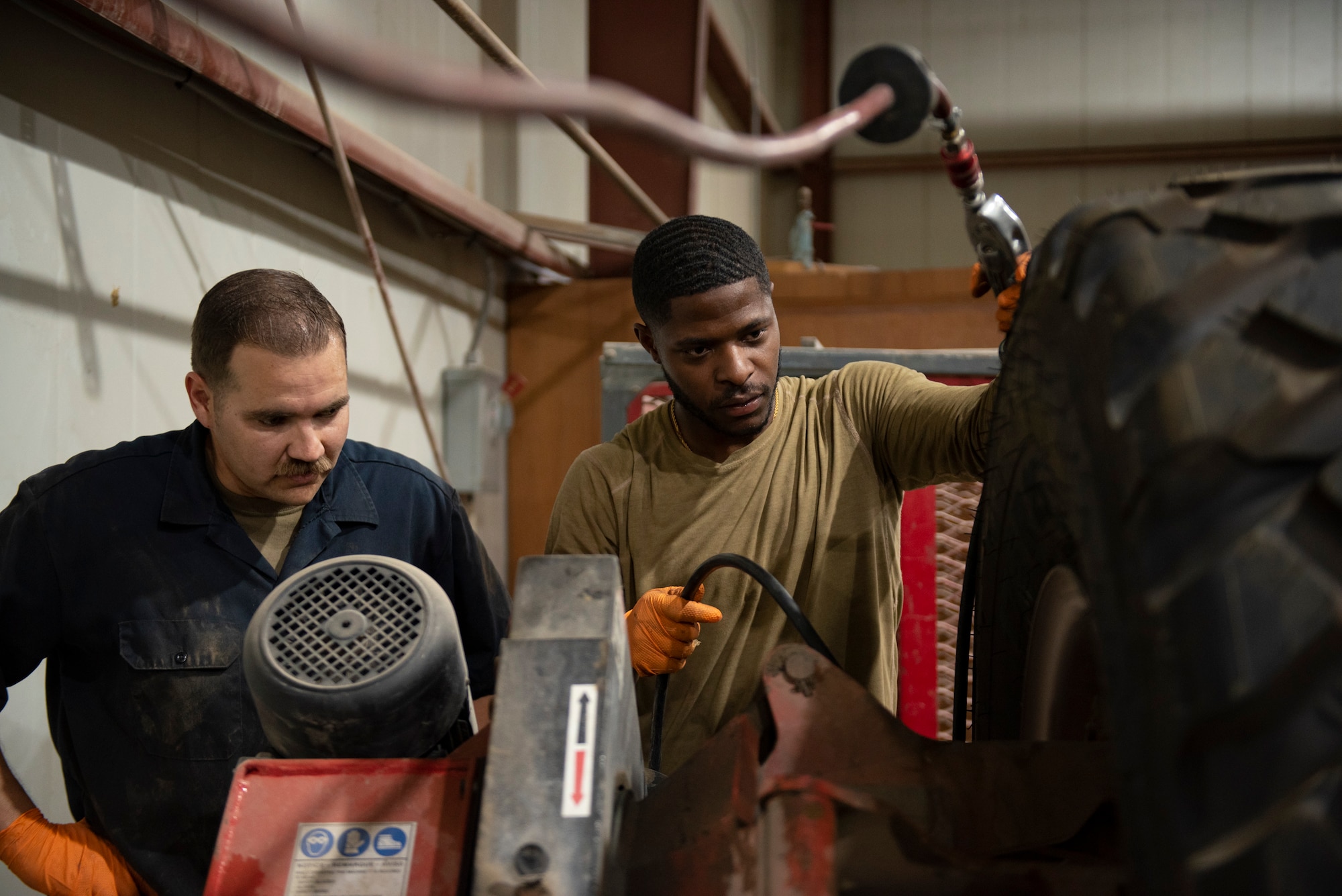 U.S. Air Force Staff Sgt. Douglas Johnson, (left) a vehicle maintainer assigned to the 386th Expeditionary Logistics Readiness Squadron, assists U.S. Air Force Senior Airman Dalfred Sonnier (right) a vehicle maintainer assigned to the 386th Expeditionary Logistics Readiness Squadron, fill a tire with air at Ali Al Salem Air Base, Kuwait, July 8, 2021.