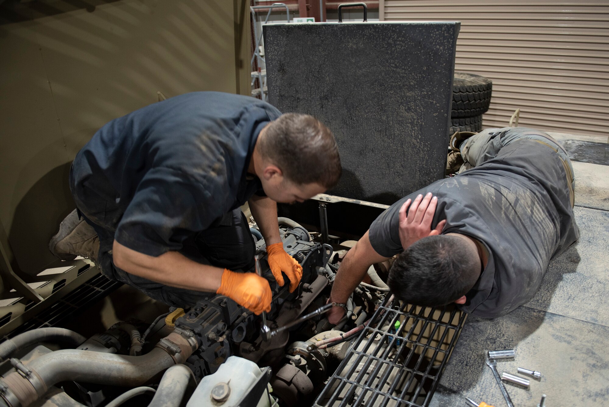 U.S. Air Force Staff Sgt. Douglas Johnson, (left) a vehicle maintainer assigned to the 386th Expeditionary Logistics Readiness Squadron, helps U.S. Air Force Staff Sgt. Brice Thompson, (right) a vehicle maintainer assigned to the 386th Expeditionary Logistics Readiness Squadron, change a starter in a MV-2 toe tractor at Ali Al Salem Air Base, Kuwait, July 8, 2021.