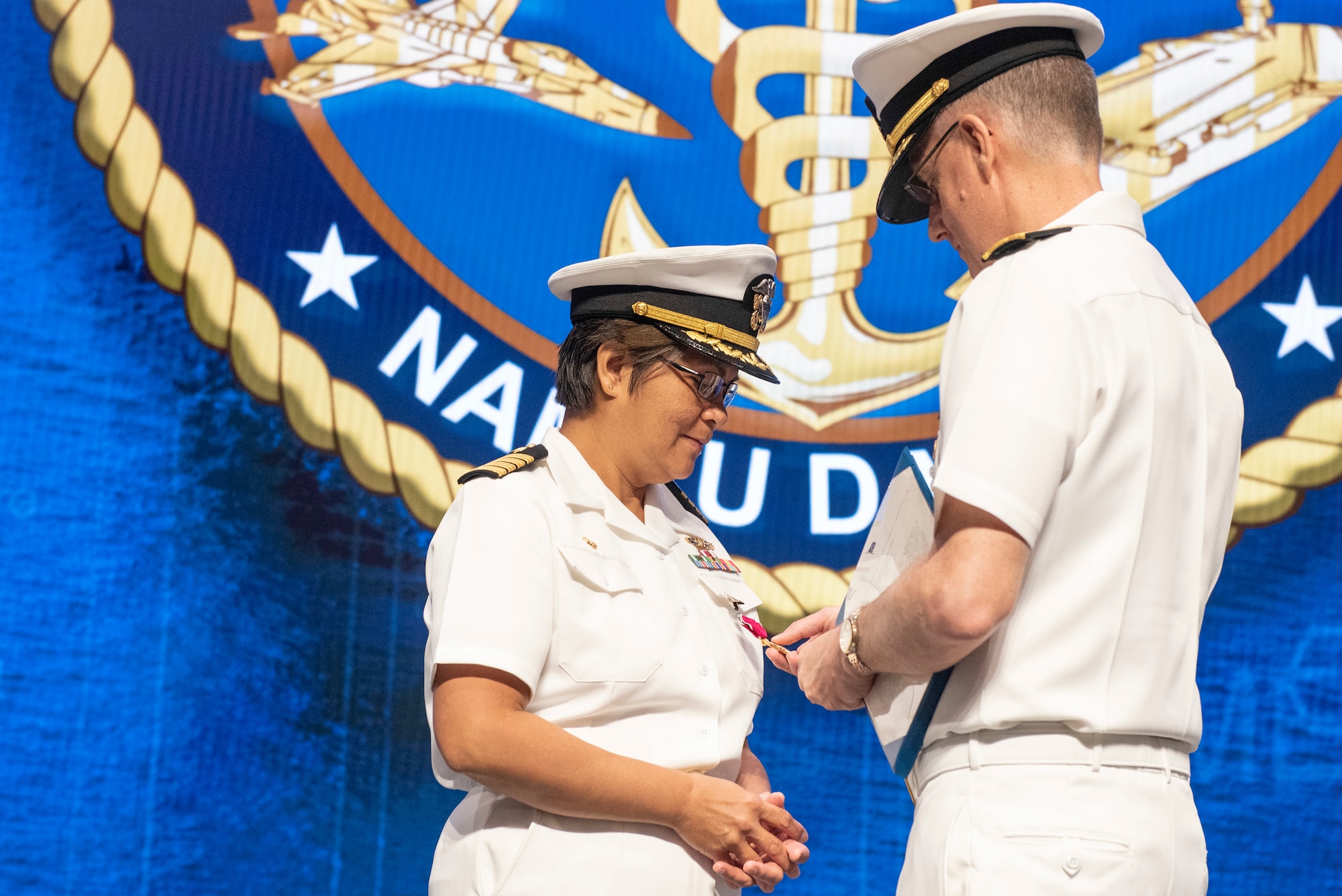 U.S. Navy Rear Admiral Tim Weber, commander of Naval Medical Forces Pacific, presents Capt. Nimfa Teneza-Mora, outgoing commander of Naval Medical Research Unit Dayton, with her Legion of Merit award, the unit’s change of command ceremony, July 9, 2021, at Wright Patterson Air Force Base, Ohio. NAMRU-Dayton is one the premier research facilities in the Navy and the unit has contributed significantly to understanding health, safety, and performance consequences of flight on humans. (U.S. Air Force photo by Wesley Farnsworth)