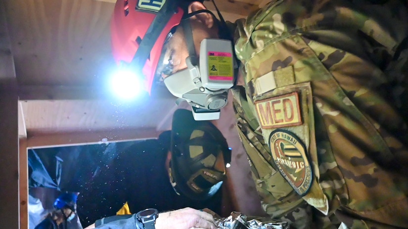 Service members crawl through a simulated collapsed structure.
