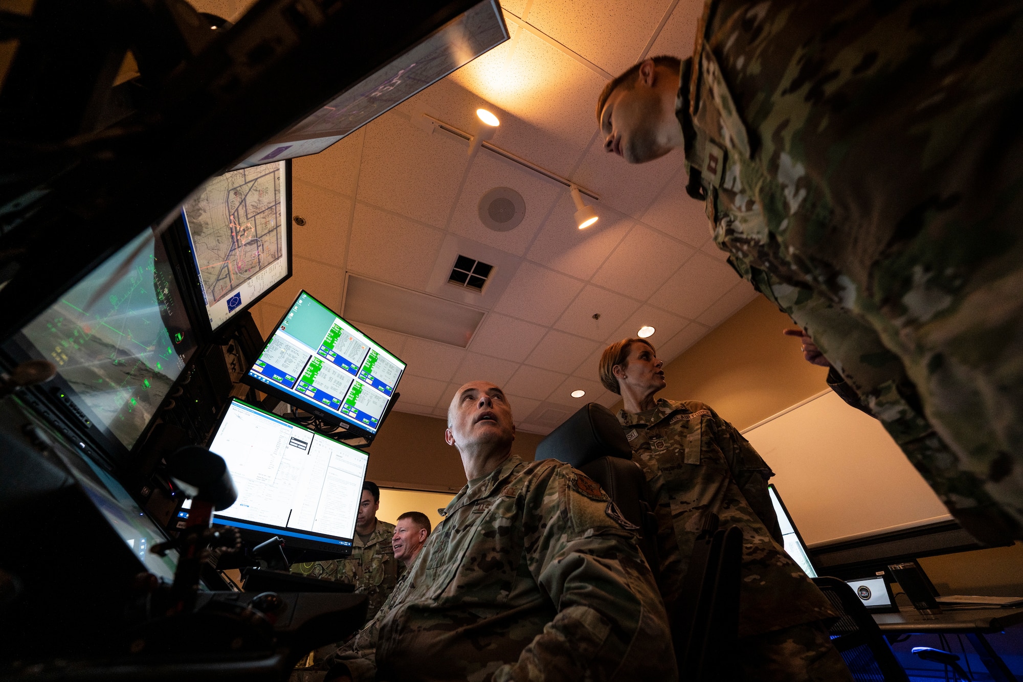Lt. Gen. Robert Miller, Surgeon General of the Air Force and Space Force, looks at a flight instructor from the pilot's seat in an  MQ-9 Reaper simulator.