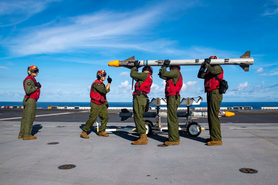 Marines carry an ordnance on the deck of a ship.