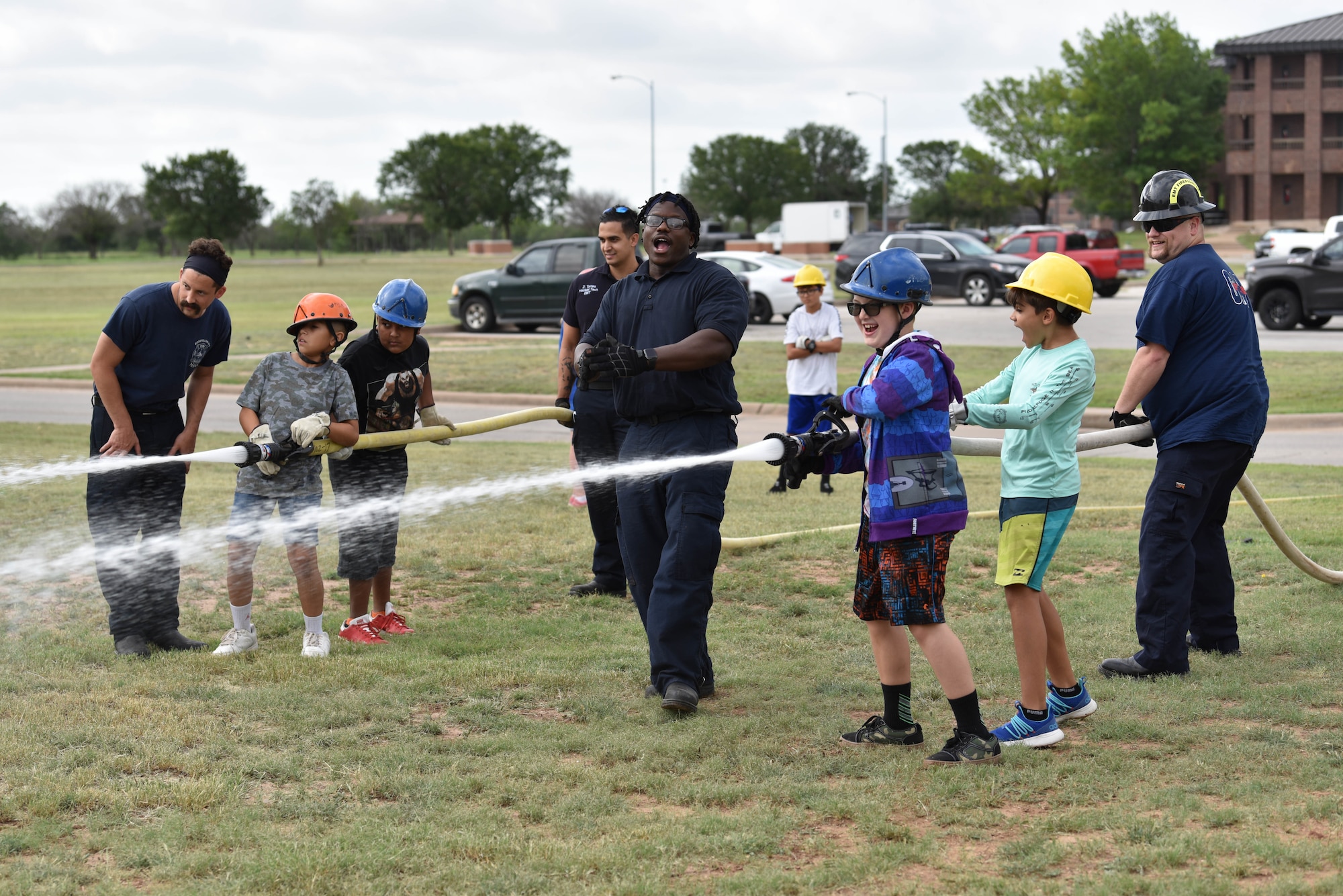 Junior firefighters, with assistance from the 17th Civil Engineer Squadron firefighters, spray fire hoses during the junior firefighter camp on Goodfellow Air Force Base, Texas, July 15, 2021. Participants were split into teams and competed against each other to knock over cones. (U.S. Air Force photo by Senior Airman Jermaine Ayers)
