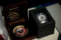 picture of an award certificate, a customized watch and a top performance coin.