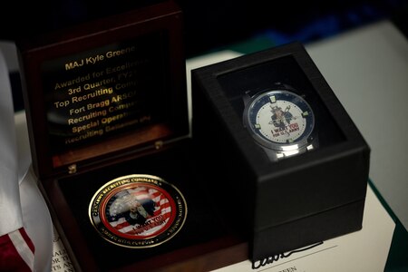 picture of an award certificate, a customized watch and a top performance coin.