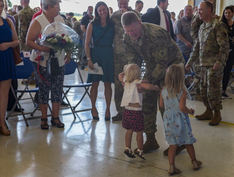 man in uniform picks up small girl