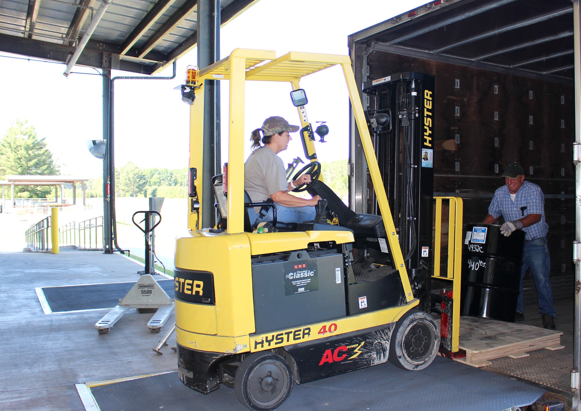 Harry Gregory, a truck driver, receives a barrel of hazardous waste from Annitta Evans, a logistics storekeeper, at the hazardous waste storage facility at Arnold Air Force Base, Tenn., on June 15, 2021. Once loaded with all the barrels that are ready for disposal, the barrels are then taken to a site off base. (U.S. Air Force photo by Deidre Moon)