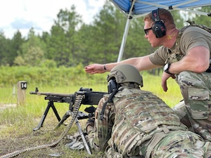 Master Sgt. Tyler Robinson, A Combat Arms Training and Maintenance (CATM) instructor with the 186th Security Forces Squadron, shows proper aiming techniques to an Airman qualifying on an M240, July 13, 2021, at the Camp Shelby firing range, Mississippi.