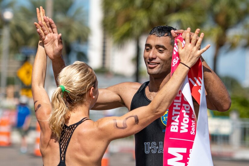 A man and woman in running uniforms give each other high fives.