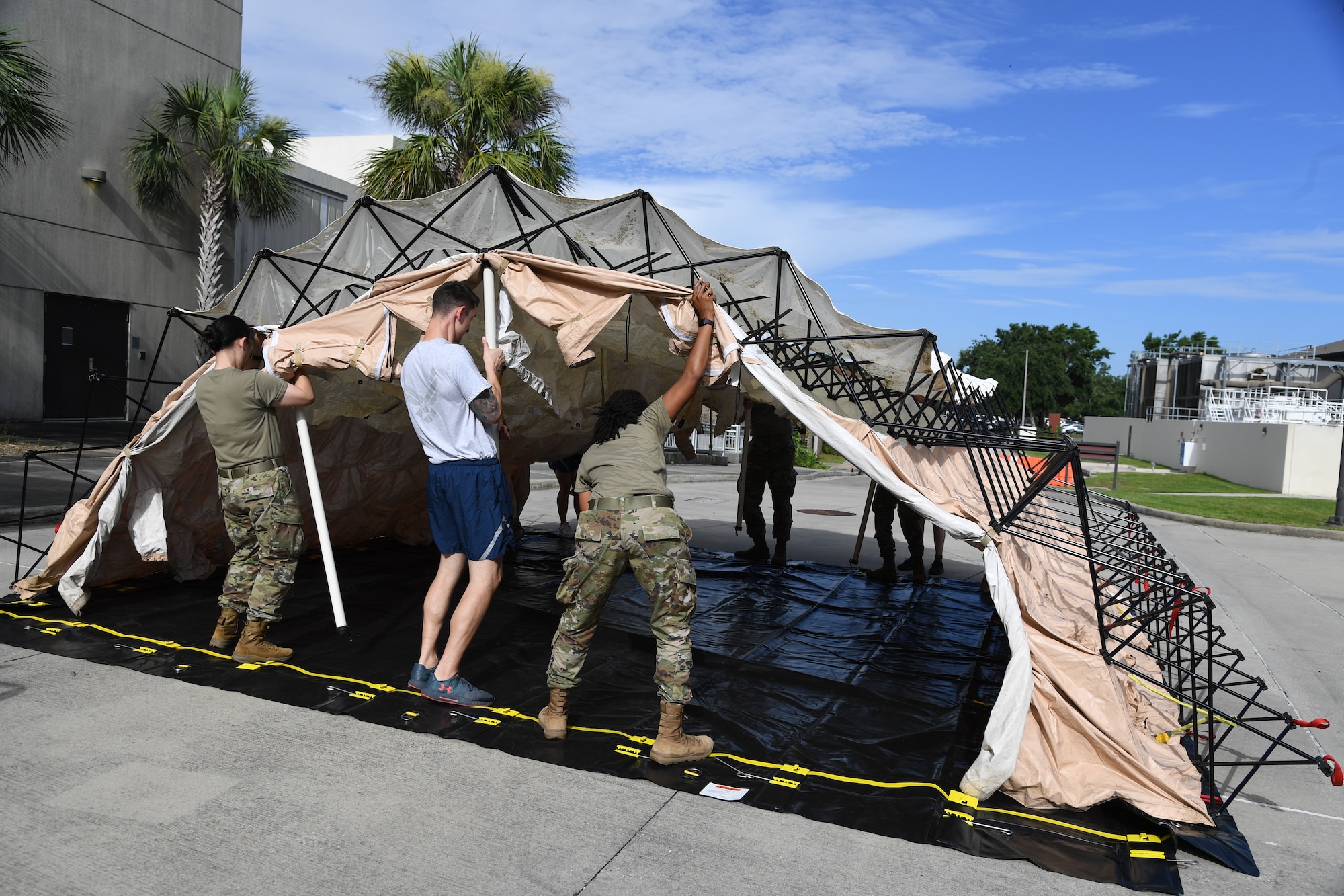 Members of the 81st Medical Group assemble a decontamination tent during an 81st MDG functional exercise behind the Keesler Medical Center at Keesler Air Force Base, Mississippi, July 15, 2021. The scenario involved a chlorine cylinder explosion causing chemical burns and other injuries on several victims. The mass casualty exercise was held to prepare for real-world events by strengthening disaster medical response capabilities. (U.S. Air Force photo by Kemberly Groue)