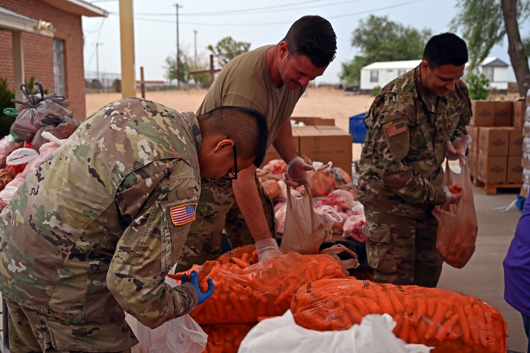 Three guardsmen prepare and organize bags of vegetables.