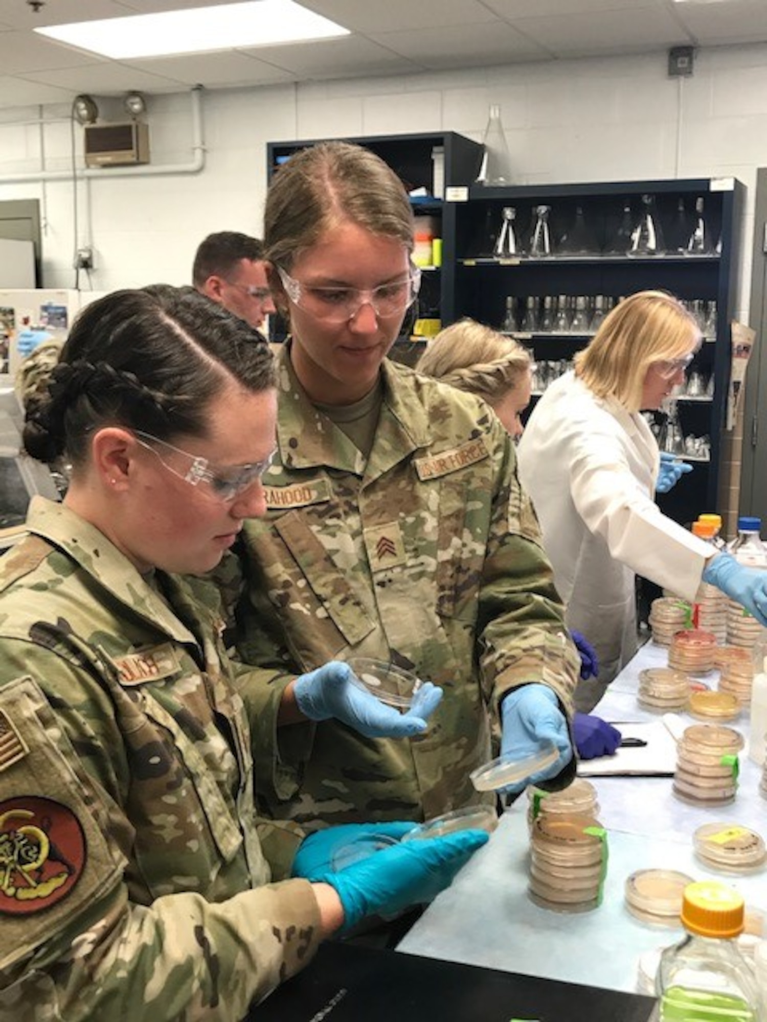 From left, U.S. Air Force Academy Cadets Julia Gundlach and Olivia Orahood, of O’Fallon, Illinois, and Alameda, California, respectively, study agar plates for bacteria colonies inside the Air Force Civil Engineer Center Readiness Laboratory at Tyndall Air Force Base, Florida.