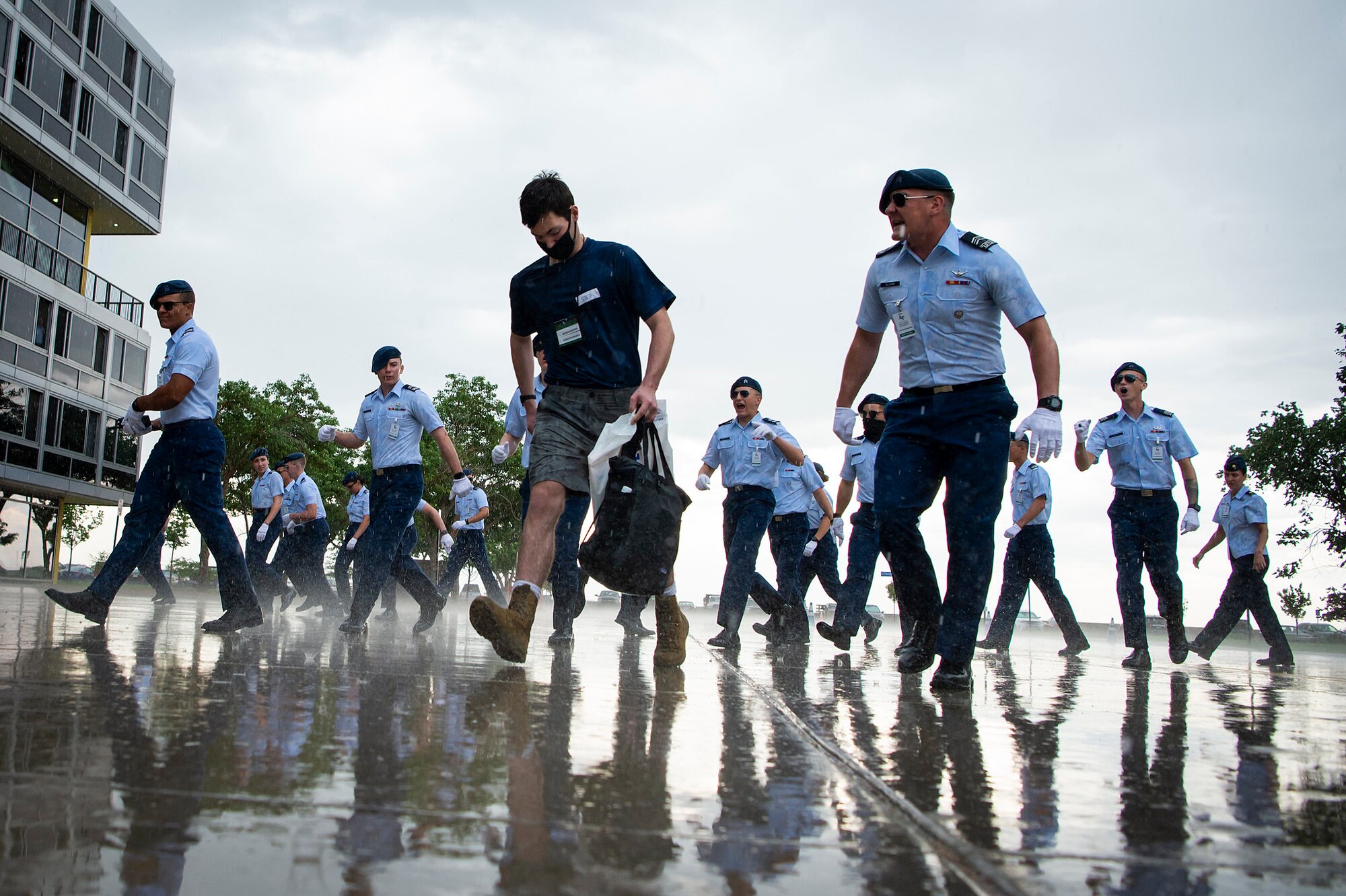 A basic cadet trainee walks in the rain on the terrazzo at the U.S. Air Force Academy surrounded by cadet cadre, June 26, 2021. Basic cadet training began that day for more than 1,100 young men and women accepted to the Academy.