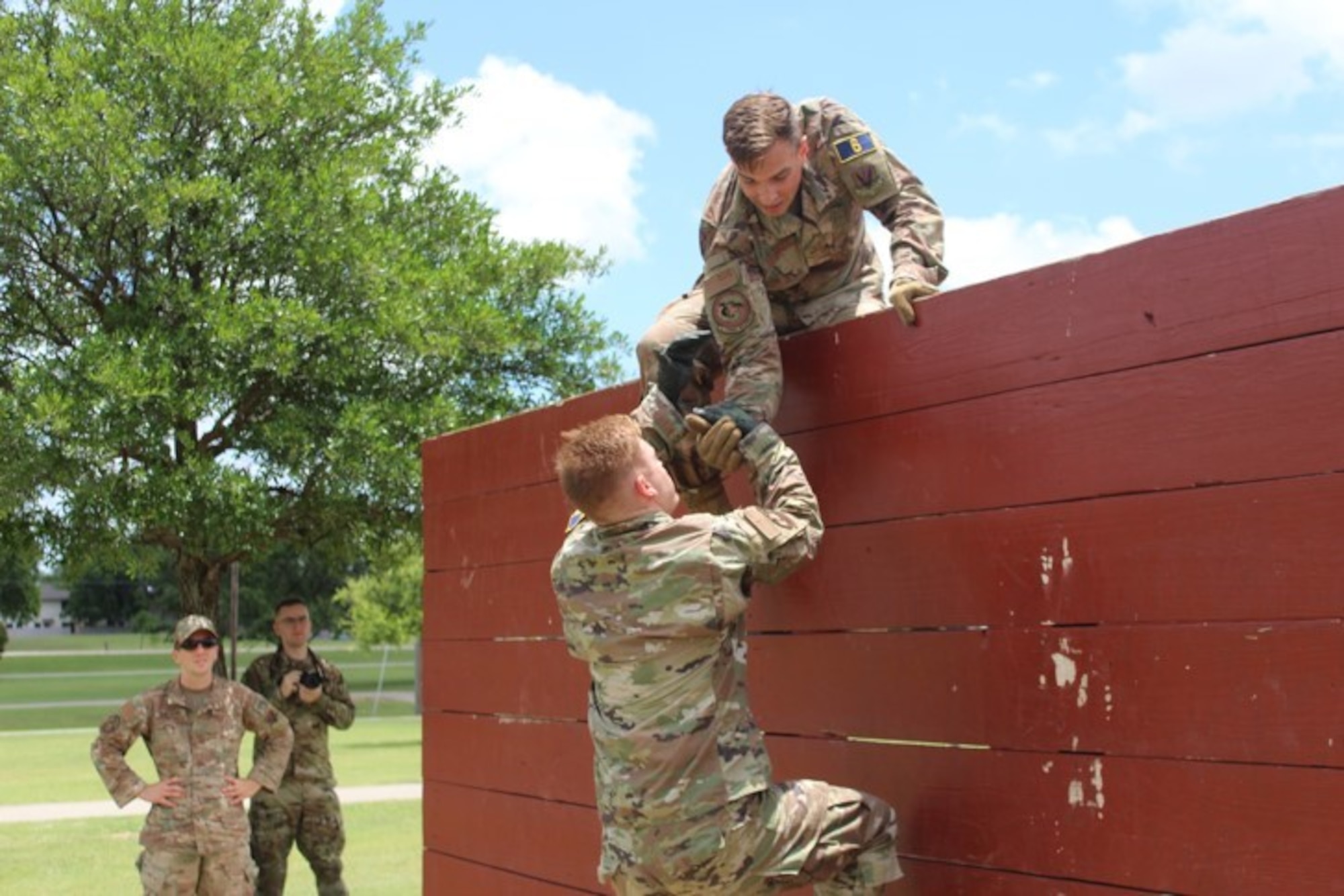 two men climbing a wall in an obstacle course