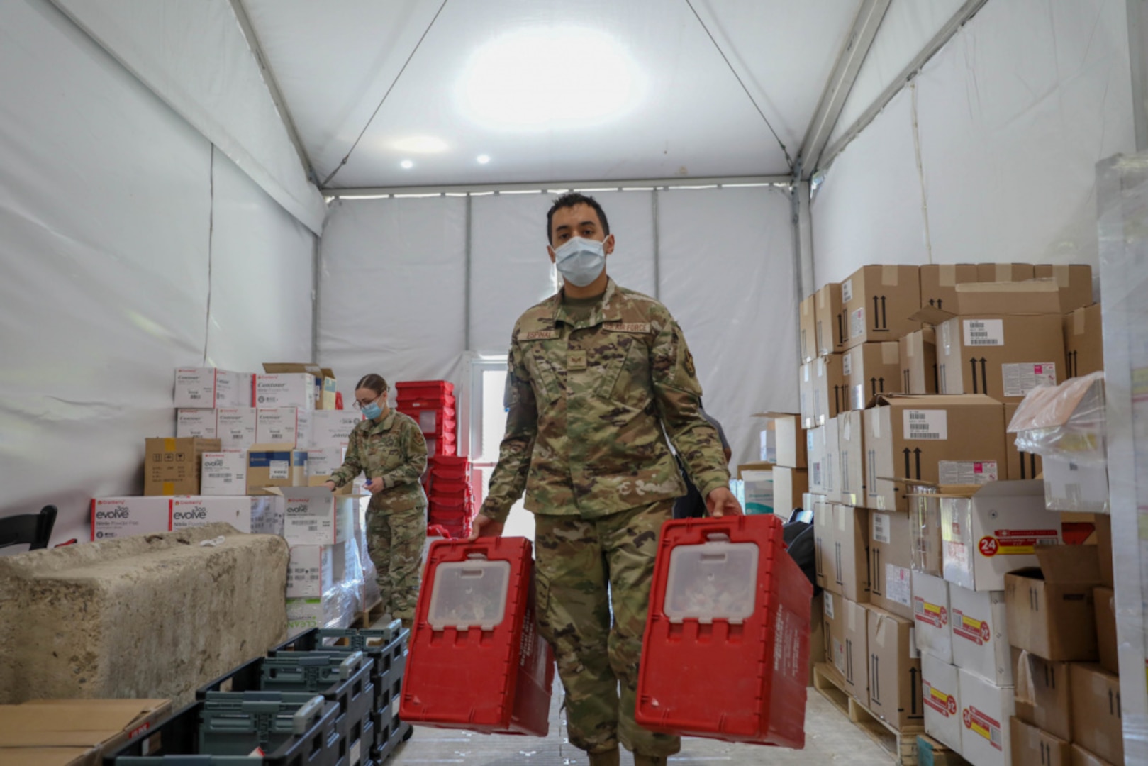 Air Force Senior Airman David Espinal, right, a Bloomfield, New Jersey native and a logistical planner assigned to the 335th Air Expeditionary Group, exchanges the hazmat containers while U.S. Air Force Senior Airman Whitney Fenninger-Stutzman, left, inventories the medical supplies at the federally-run pilot Community Vaccination Center at the Greenbelt Metro Station in Greenbelt, Maryland, May 13, 2021. Deliveries of medical supplies such as these are made possible by the Defense Logistics Agency Troop Support Medical’s Medical Surgical Prime Vendor program, named “Best in Class” by the Office of Management and Budget in July 2021.