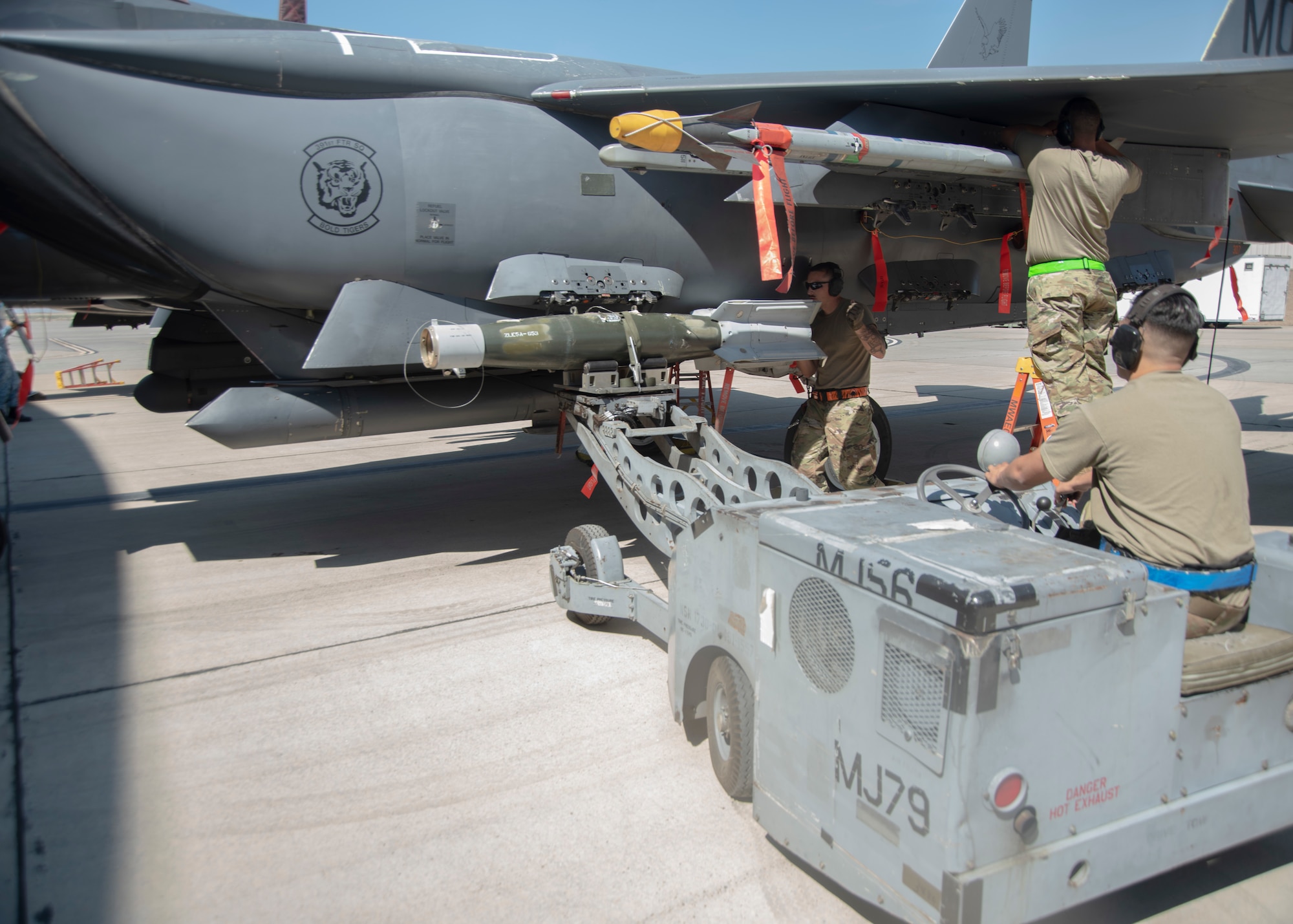Three Airmen work together to load and secure a Guided Bomb Unit-12 and an Air Intercept Missile-9X to a F-15E Strike Eagle.