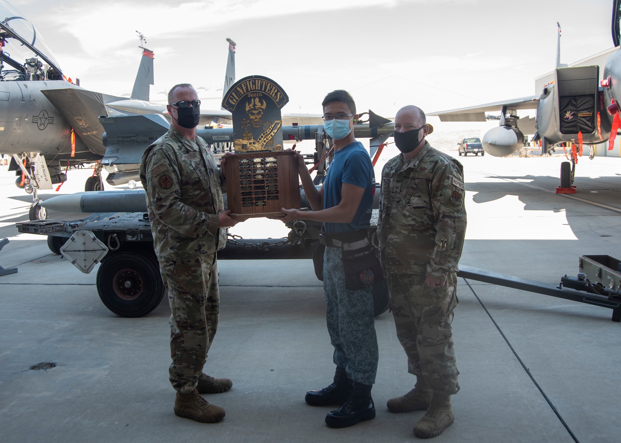 Two Airmen from the United States Air Force and one Airman from Republic of Singapore Air Force pose for a photo with the Jammer Vehicle Competition trophy.