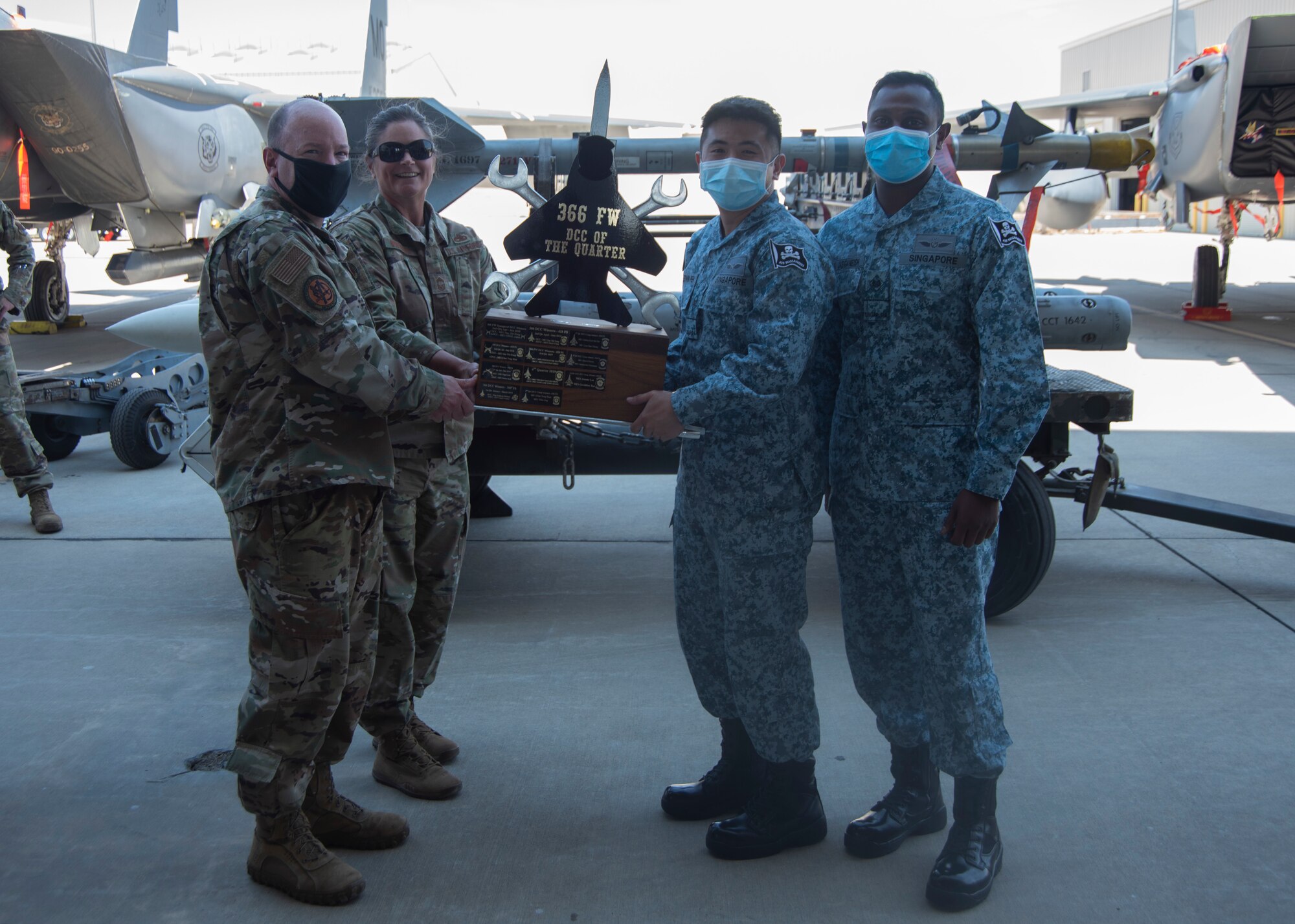 Two Airmen from the United States Air Force and two Airmen from Republic of Singapore pose for a photo with the Dedicated Crew Chief Competition trophy.