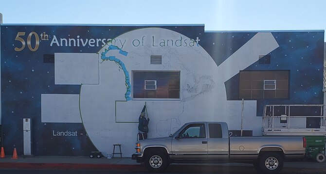 Ann Thompson, City of Lompoc Mural Society curator, started painting the earth of the mural on Ocean Avenue and I street June 27, 2021 in Lompoc, California. The mural will be implementing the history of the progression of the Landsat satellites numbers one through eight. (U.S. Space Force photo by Airman First Class Tiarra Sibley)