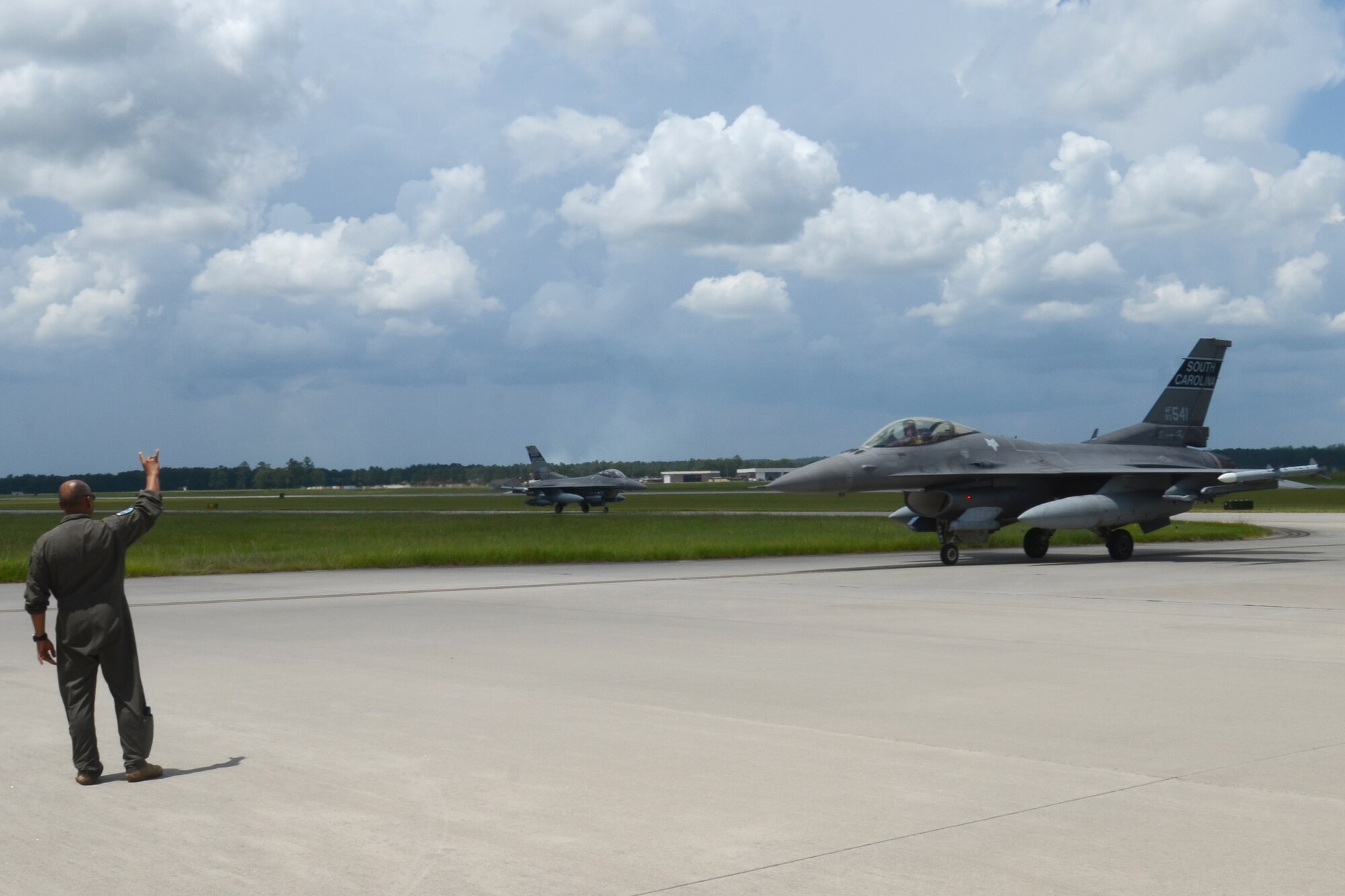 U.S. Air Force Col. Akshai Gandhi, 169th Fighter Wing commander, gives the “Swamp Fox” hand signal to a F-16 fighter jet pilot returning home July 16, 2021 to McEntire Joint National Guard Base, South Carolina.  U.S. Air Force personnel from the 169th Fighter Wing recently deployed to Prince Sultan Air Base, Kingdom of Saudi Arabia. "Swamp Fox" Airmen from the South Carolina Air National Guard’s 169th Fighter Wing have been deployed to PSAB for the past three months to project combat power and help bolster defensive capabilities against potential threats in the region. (U.S. Air National Guard photo by Lt. Col. Jim St.Clair, 169th Fighter Wing Public Affairs)