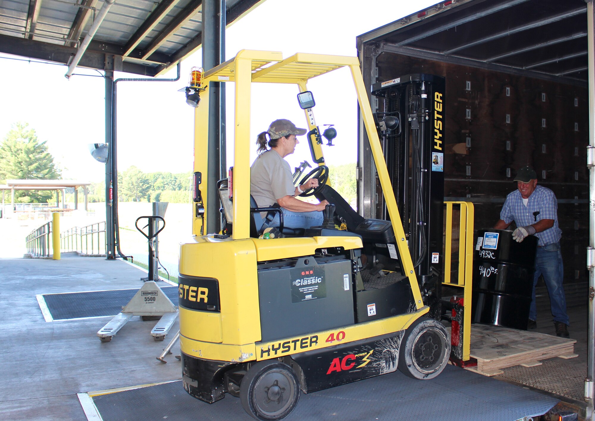 Harry Gregory, a truck driver, receives a barrel of hazardous waste from Annitta Evans, a logistics storekeeper, at the hazardous waste storage facility at Arnold Air Force Base, Tenn., on June 15, 2021. Once loaded with all the barrels that are ready for disposal, the barrels are then taken to a site off base. (U.S. Air Force photo by Deidre Moon)