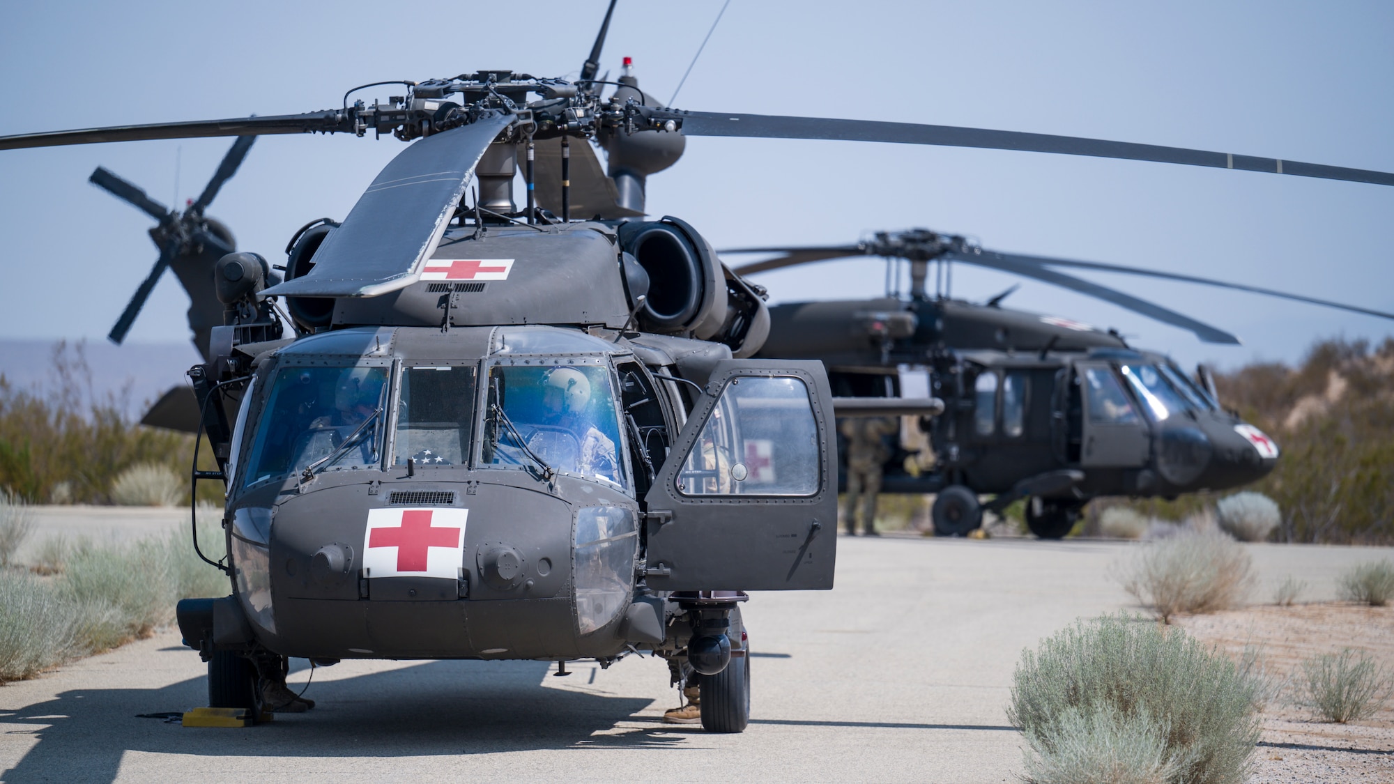 Two UH-60 Blackhawks from C Company, "Desert Dustoff," 2916th Aviation Battalion, 916th Support Brigade, out of Fort Irwin, prepare to depart from the base clinic's helipad following air medevac training at Edwards Air Force Base, California, July 15. Team Edwards medical personnel were trained on proper patient loading procedures and were then given familiarization flights around the medical facility. (Air Force photo by Giancarlo Casem)