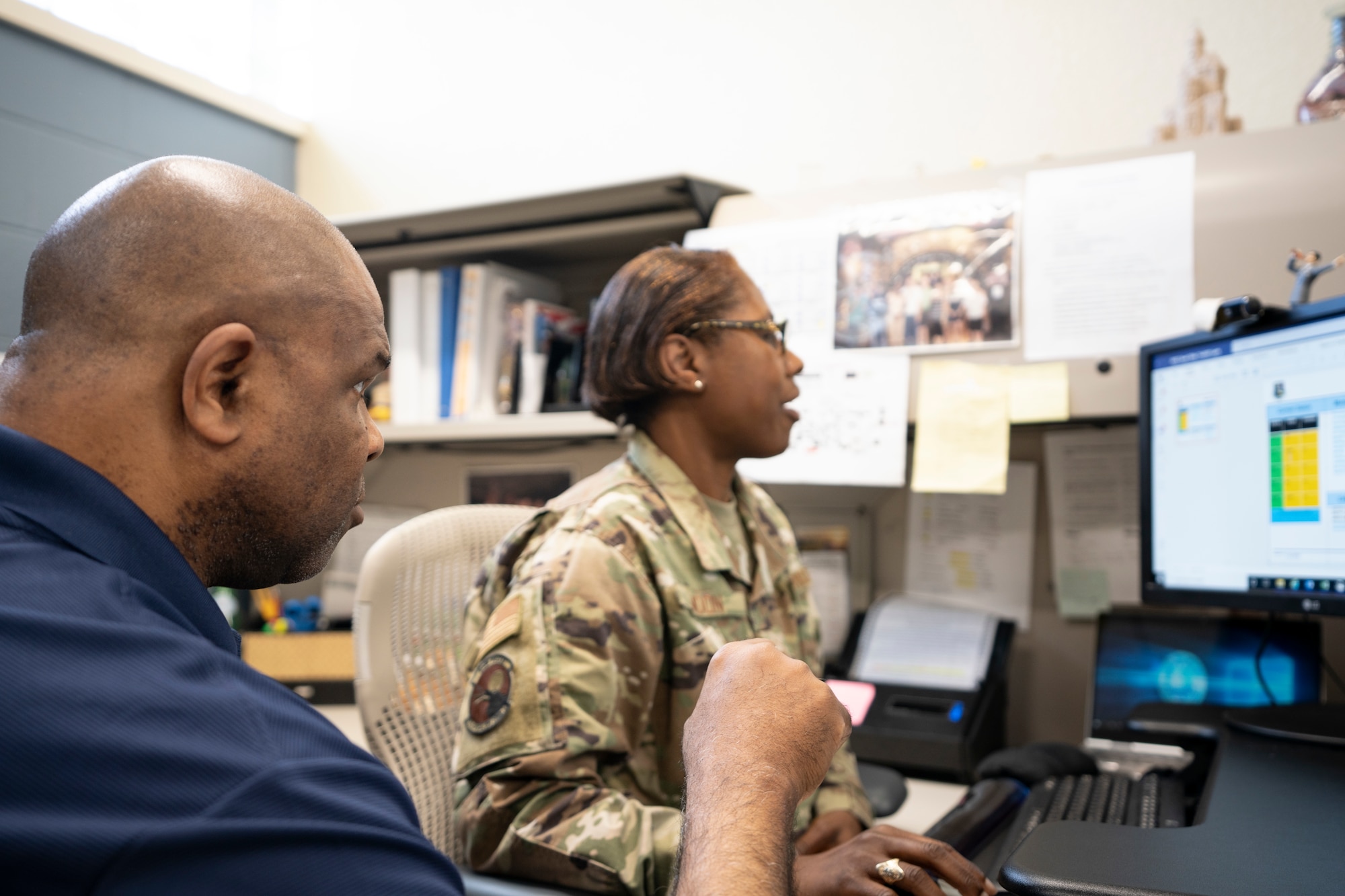 Man looks at slides on a computer with an Airman.