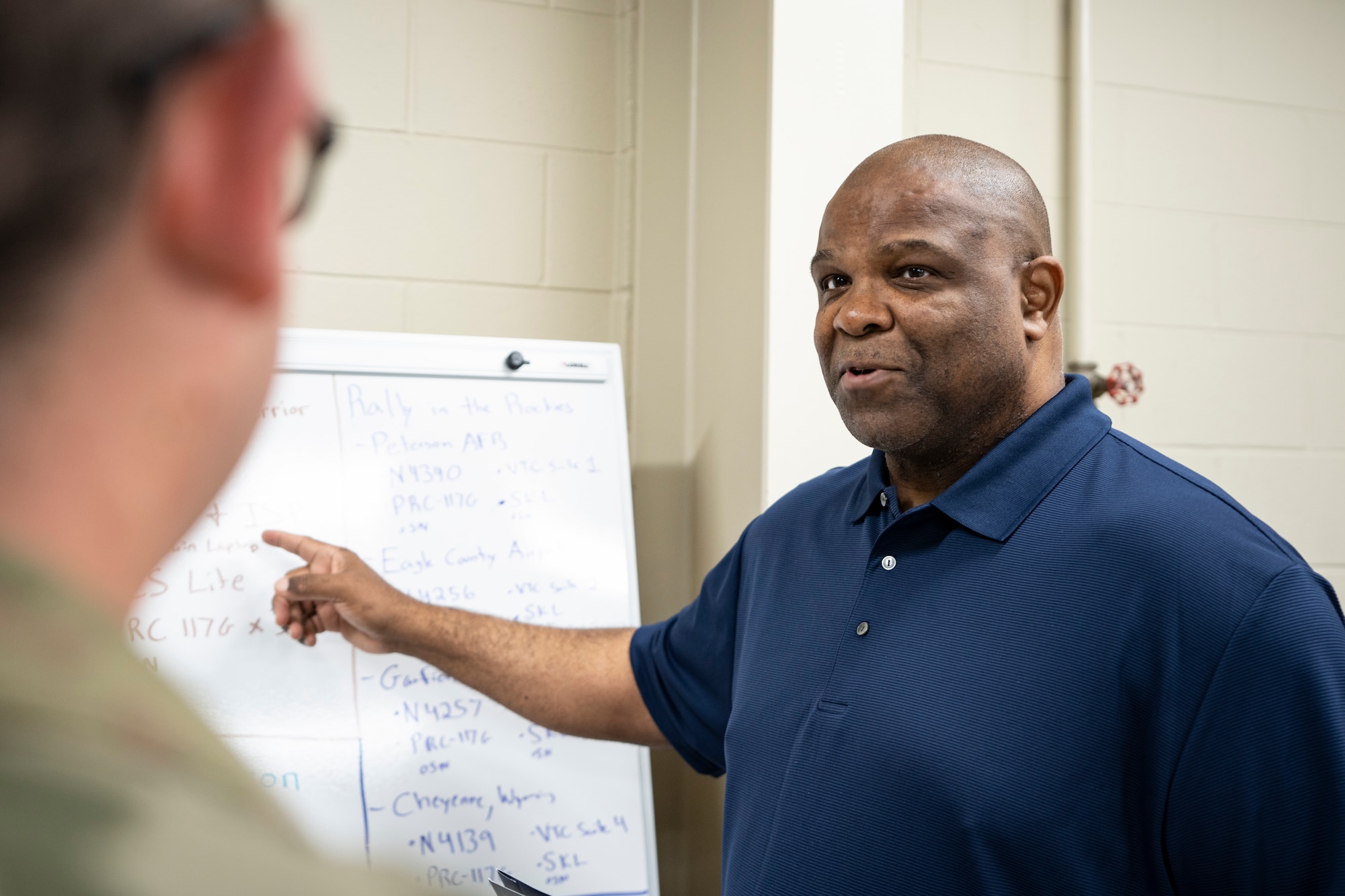 Man points to white board with miscellaneous information.