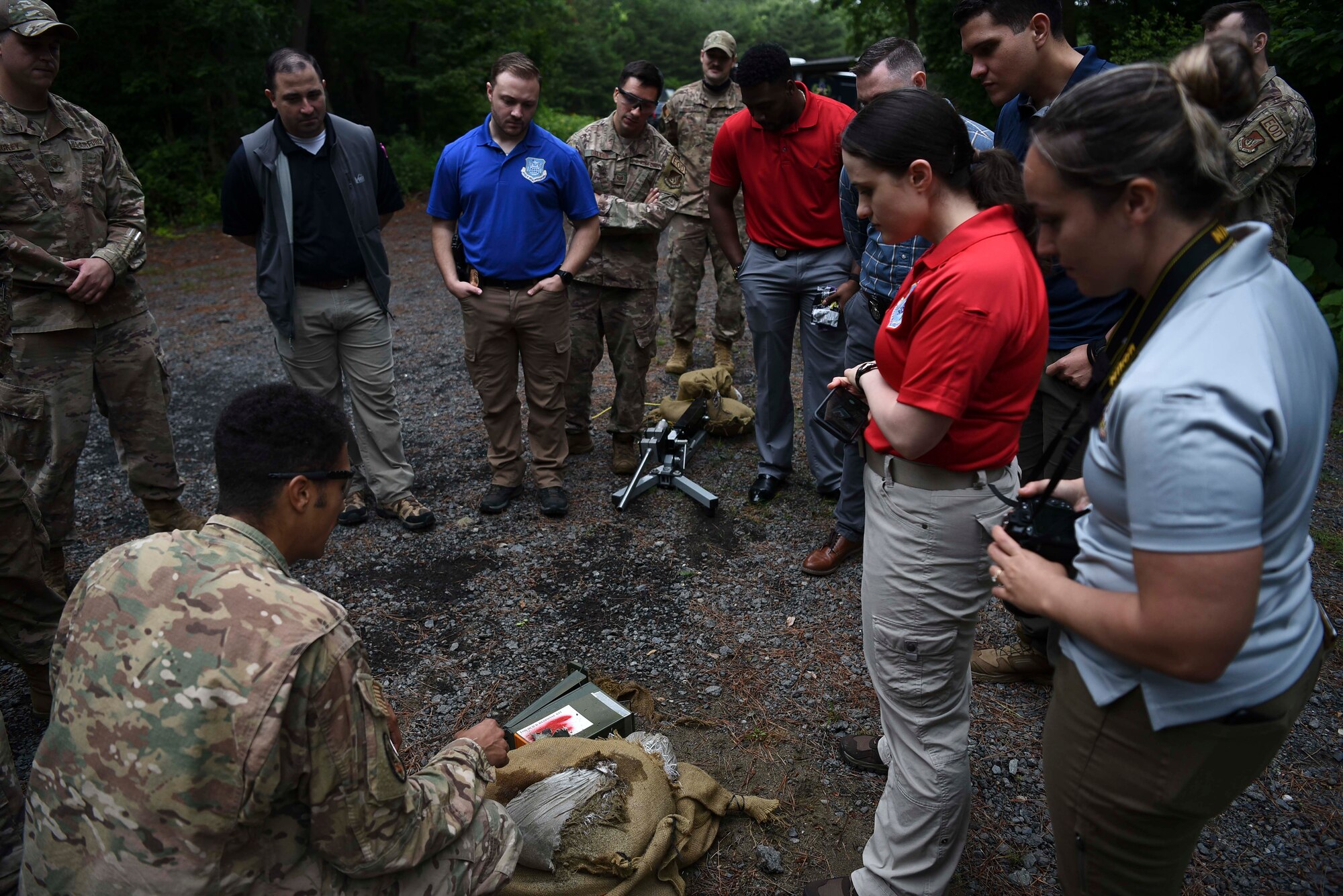 Military members stand around a prop bomb made with an ammo can that's been shot with an anti-bomb device.