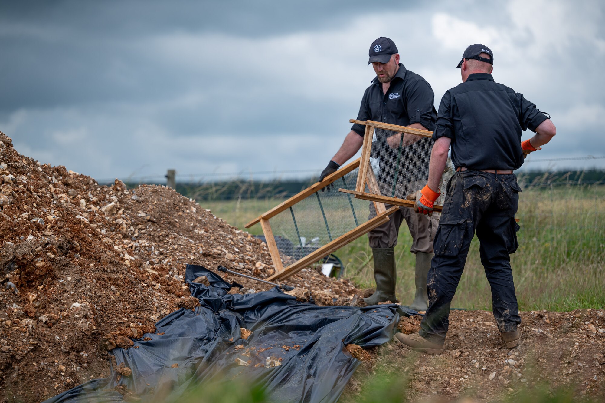 Gregory Ashcroft, squad lead for the American Veterans Archeological Recovery group, left, and Dr. Steven Humphreys, CEO of AVAR, search for remains of fallen service members during a B-24 Liberator excavation at Park Farm in Arundel, England, July 8, 2021. AVAR is conducting the dig in conjunction with the Defense POW/MIA Accounting Agency in an effort to recover those still missing in action. (U.S. Air Force photo by Senior Airman Koby I. Saunders)