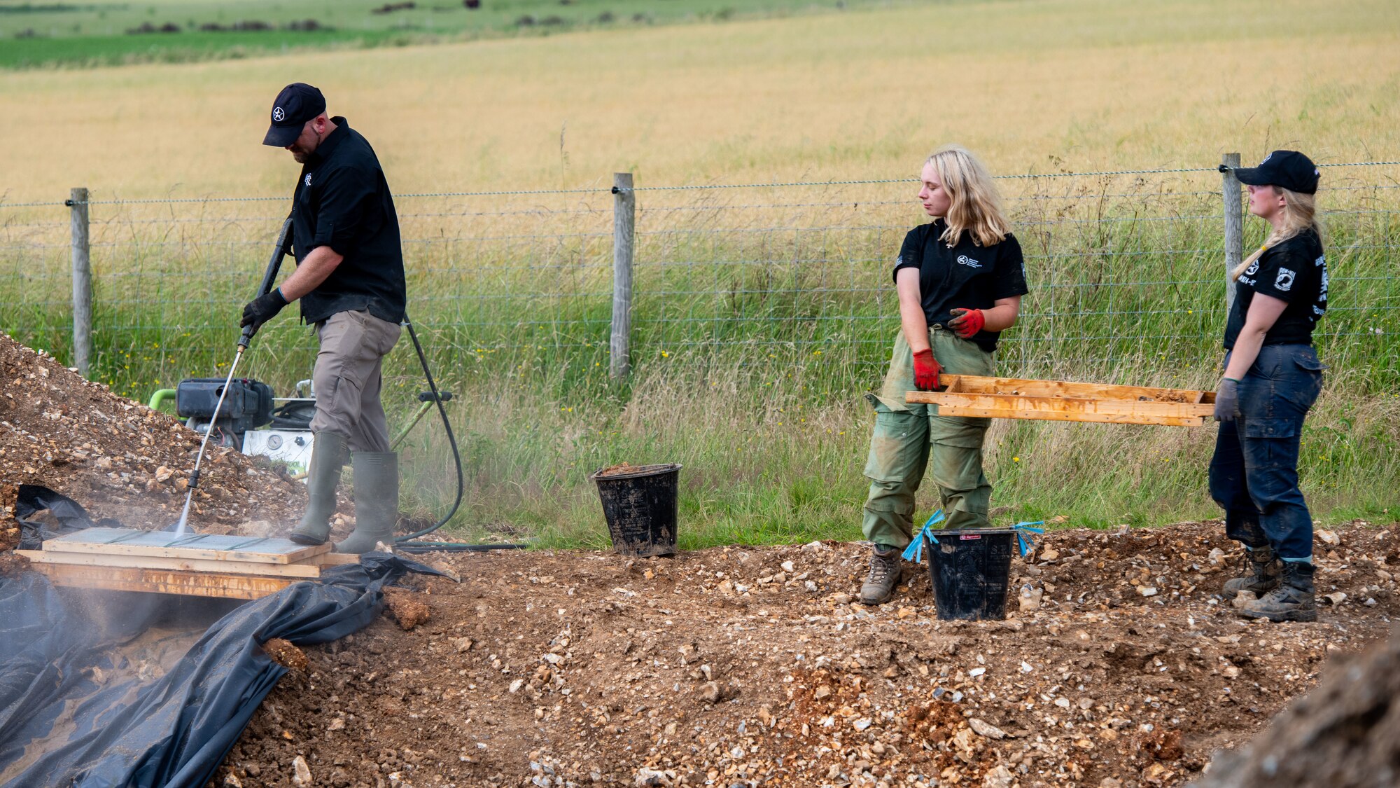 Volunteers with American Veterans Archaeological Recovery use a power washer to clean clay from potential finds during an excavation of a B-24 bomber at Park Farm in Arundel, England, July 8, 2021. AVAR is conducting the dig in conjunction with the Defense POW/MIA Accounting Agency in an effort to recover those still missing in action. (U.S. Air Force photo by Airman 1st Class Cedrique Oldaker)