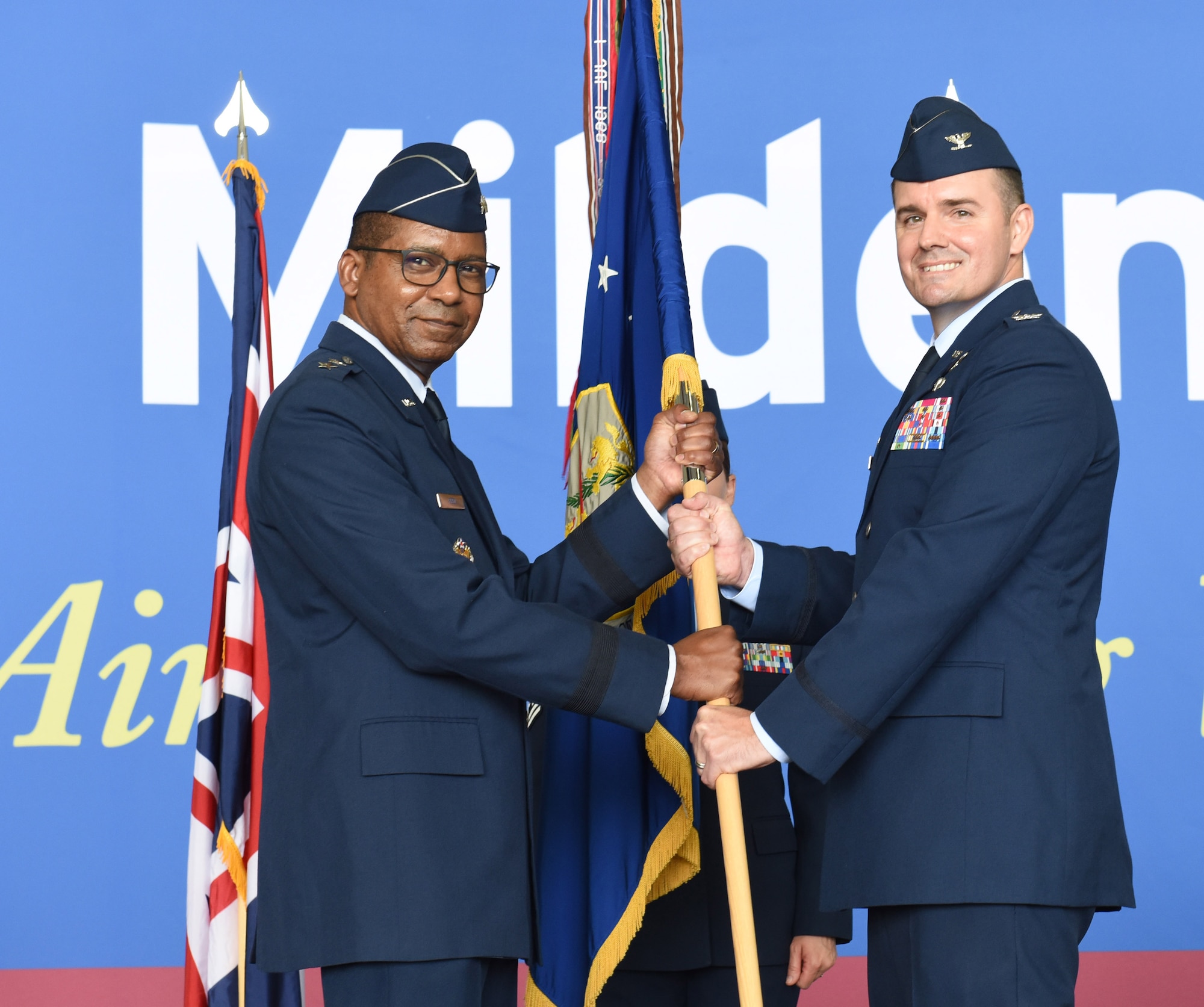 U.S. Air Force Maj. Gen. Randall Reed, left, 3rd Air Force commander, and Col. Gene Jacobus, 100th Air Refueling Wing commander, pose for a photo with the wing guidon during the 100th ARW change of command ceremony at Royal Air Force Mildenhall, England, July 19, 2021. The passing of the unit guidon during a change of command ceremony is a symbolic representation of passing authority to the incoming commander. (U.S. Air Force photo by Karen Abeyasekere)