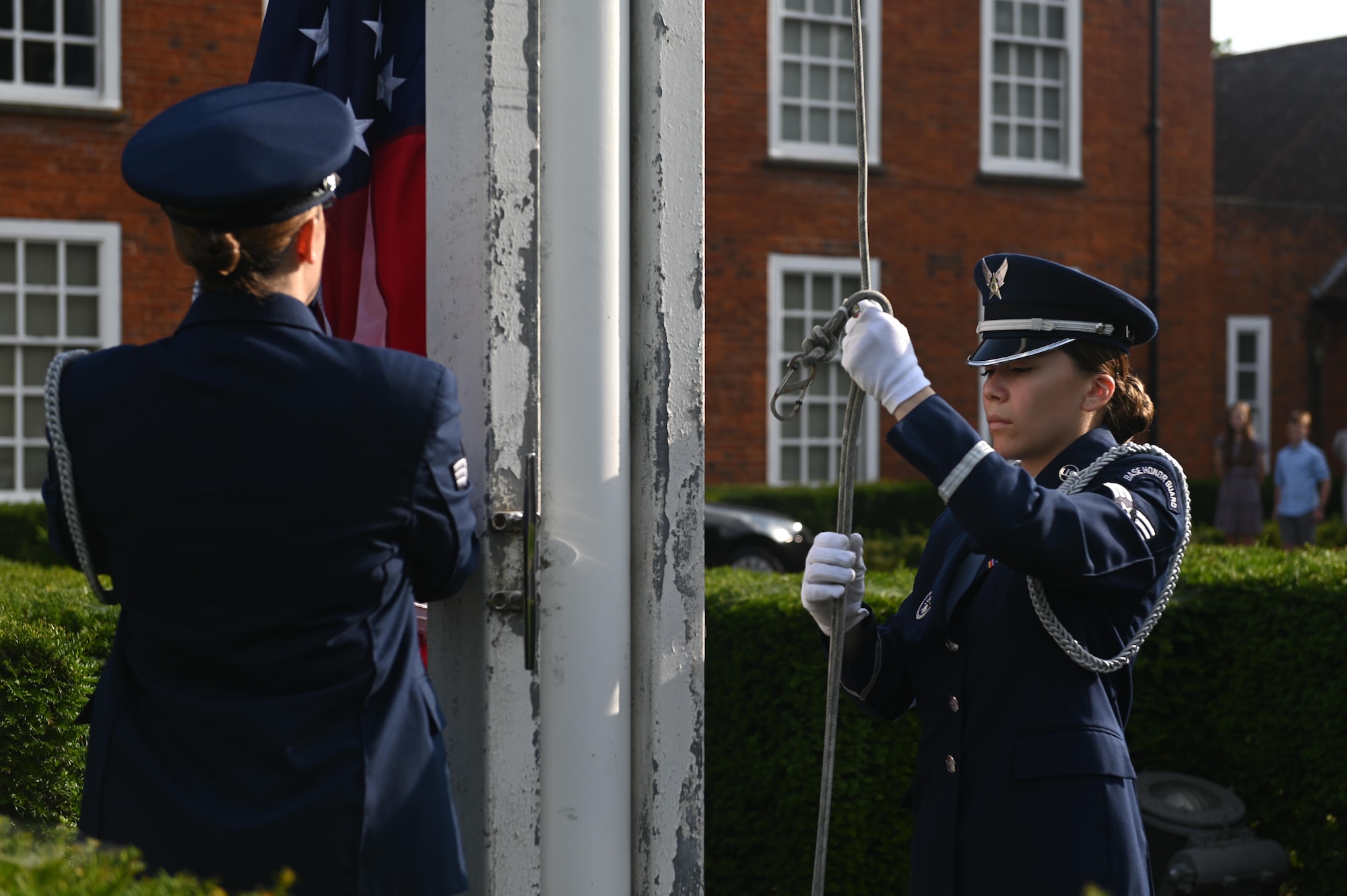 Members from the 100th Air Refueling Wing honor guard lower a flag at Royal Air Force Mildenhall, England, July 19, 2021. The honor guard swapped out flags to signify the change of command from one base commander to another. (U.S. Air Force photo by Staff Sgt. Matthew J. Wisher)