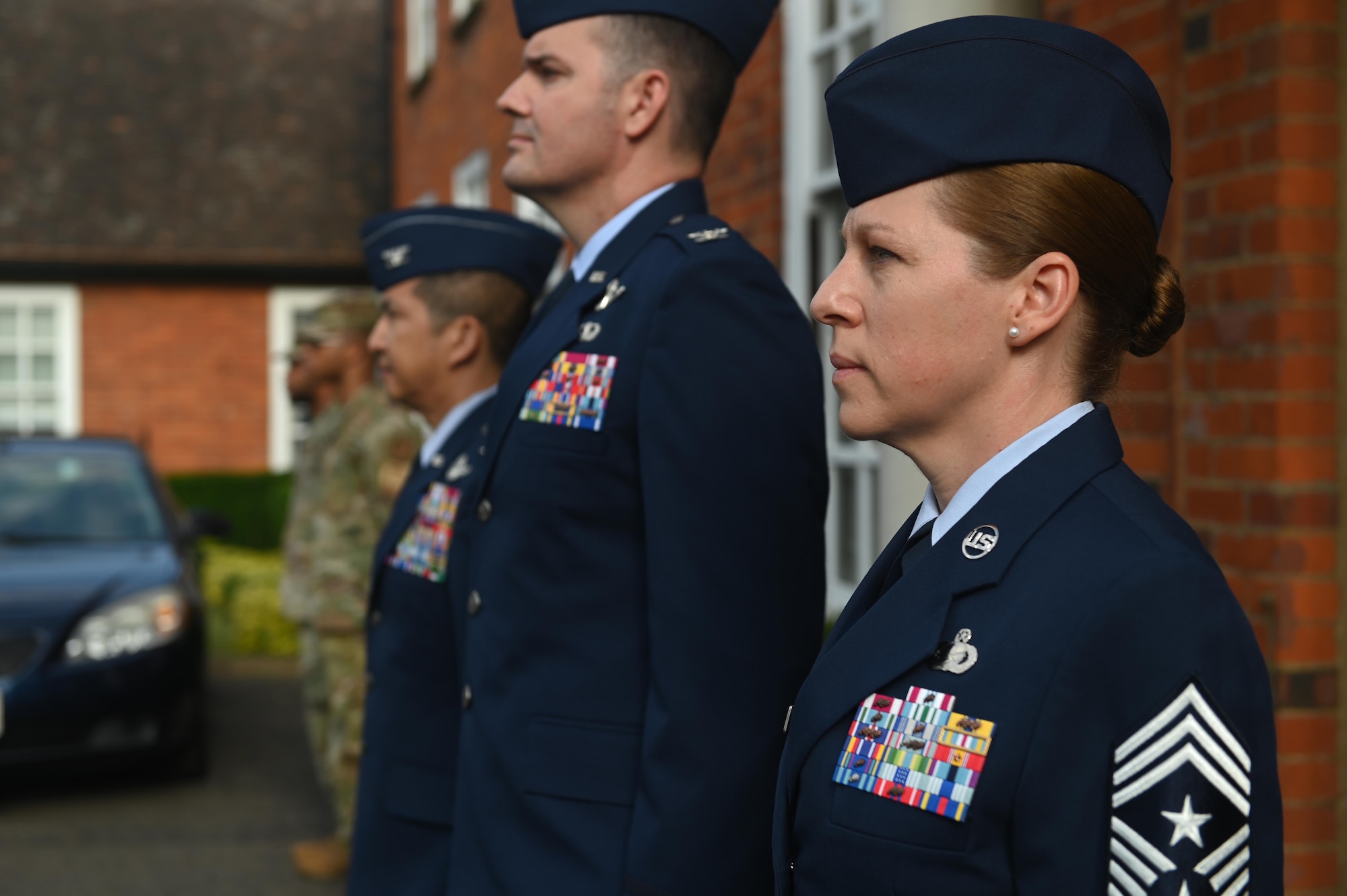 U.S. Air Force Chief Master Sgt. Kathi Glascock, 100th Air Refueling Wing command chief, stand while the base honor guard team lowers a flag at Royal Air Force Mildenhall, England, July 19, 2021. The honor guard folded a flag to present to the Col. Troy Pananon on his last day as the 100th ARW commander. (U.S. Air Force photo by Staff Sgt. Matthew J. Wisher)
