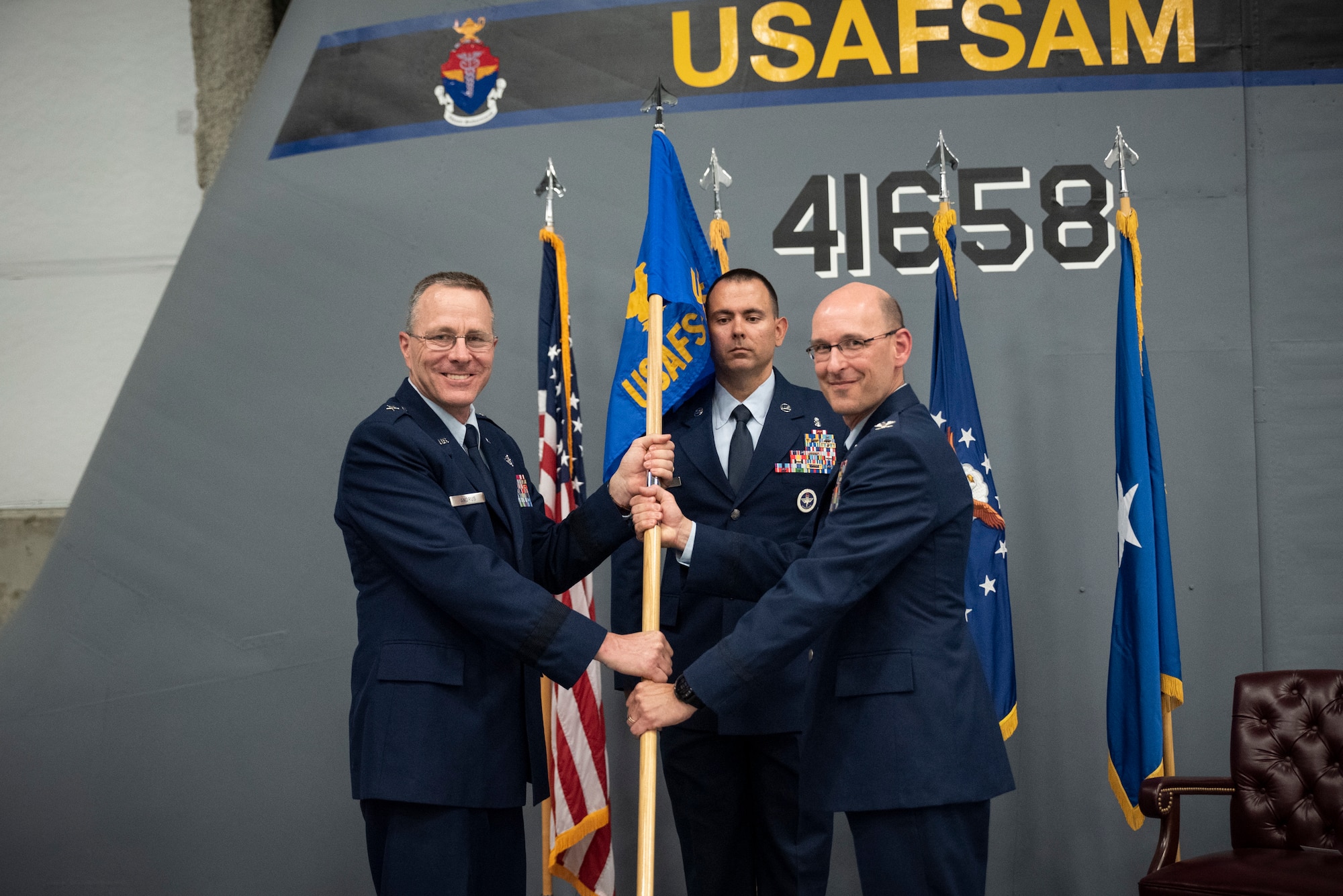 During an assumption of command ceremony July 19, 2021, Brig. Gen. John Andrus, 711th Human Performance Wing commander, passes the flag to Col. Tory Woodard, the newest commander of the United States Air Force School of Aerospace Medicine, signifying the school’s change of command. USAFSAM is one of two mission units in the Air Force Research Laboratory’s 711th Human Performance Wing. (U.S. Air Force photo/Richard Eldridge)