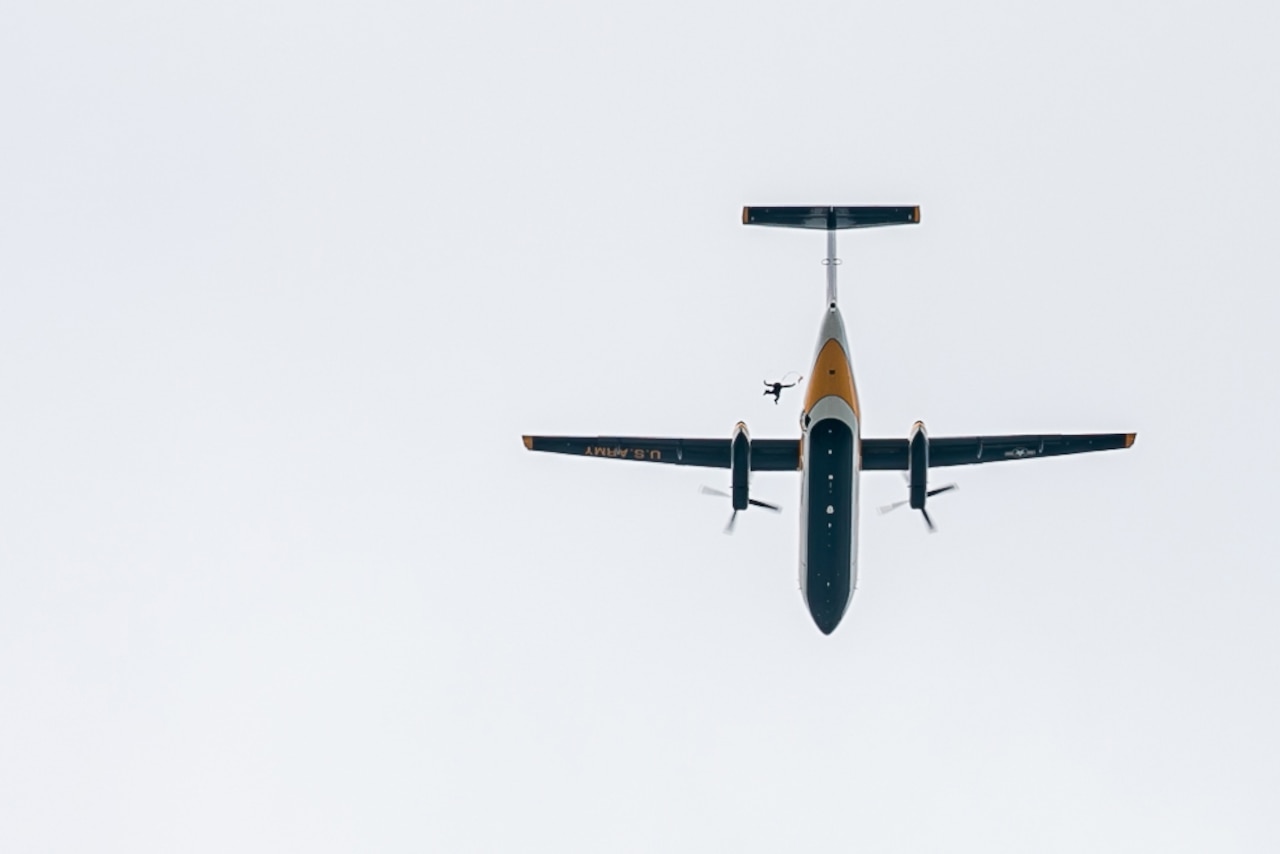 A soldier jumps out of an airborne aircraft.