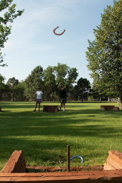U.S. Air Force Tech. Sgt. Ryan Payne, right, and U.S. Air Force Staff Sgt. Codie Sechi both with the 561st Network Operations Squadron play horseshoes during Sports and Field Day at Peterson Air Force Base, Colorado, July 16, 2021.  The Sports and Field Day included a variety of physical and mental activities, food and prizes. (U.S. Space force photo by Airman Aaron Edwards)