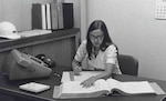 woman looking a large book with frieden calculator to her left