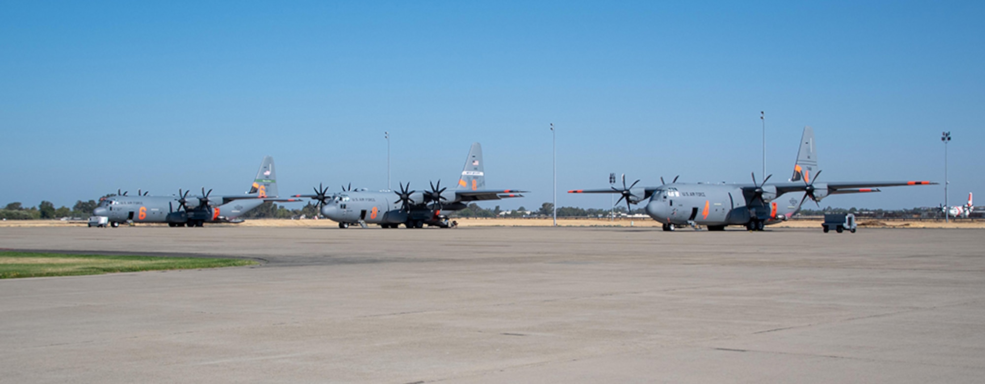 Three Air National Guard C-130s await launch orders July 14, 2021, at CAL FIRE Air Tanker Base, McClellan Park, Calif. The Department of Defense, through the commander, U.S. Northern Command (USNORTHCOM), supports the National Interagency Fire Center in wildland firefighting operations.