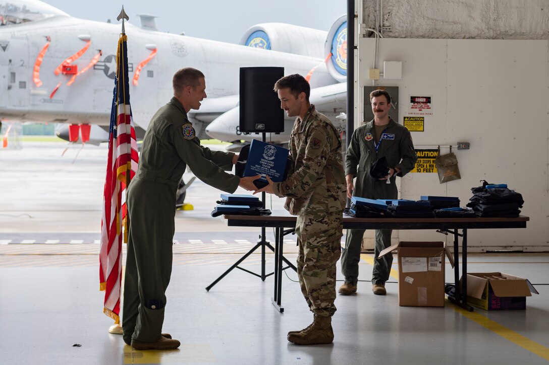 Photo of an Airman receiving coveralls and a certificate