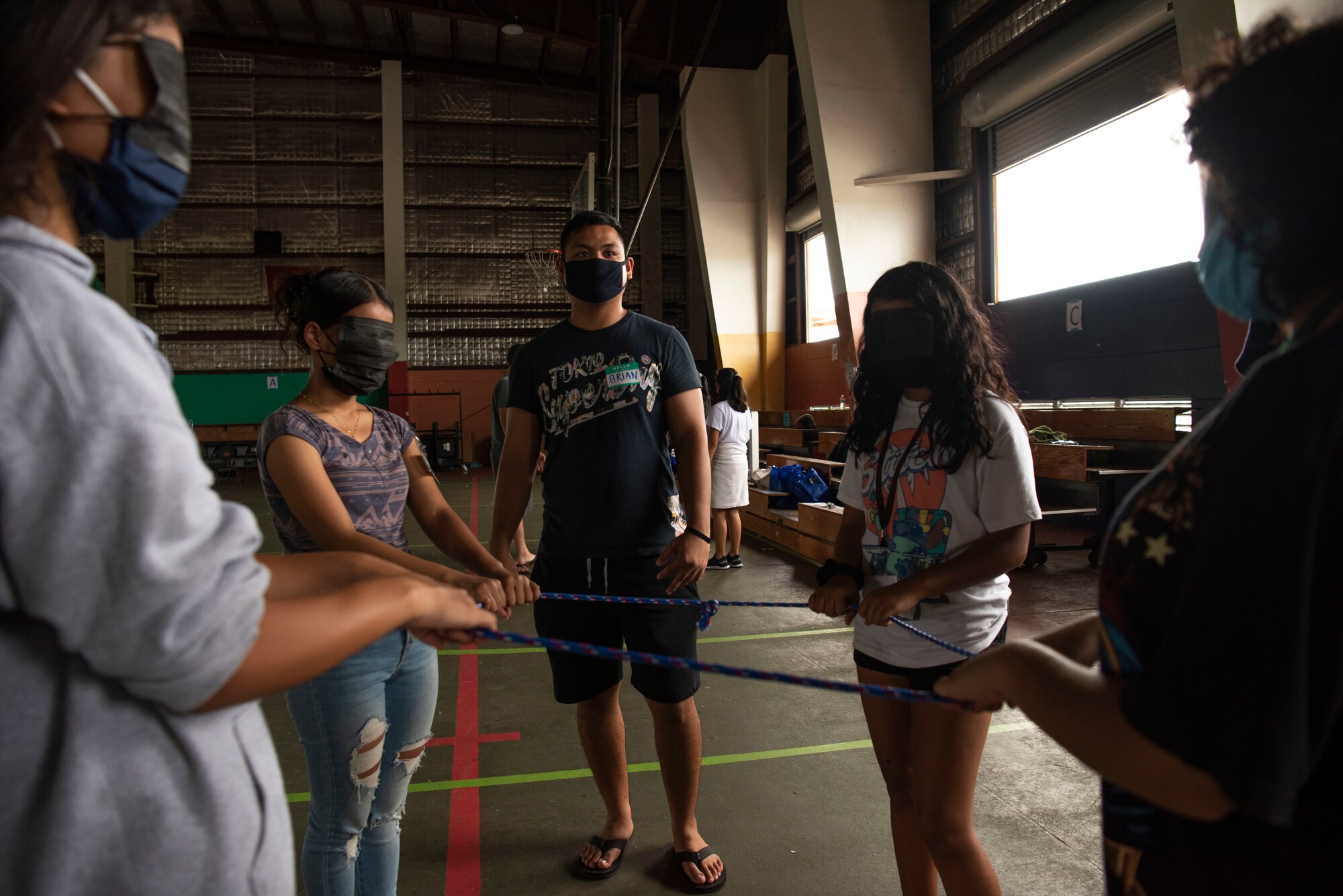 Brian Javier, Mañe'lu volunteer, guides his group of middle and high school students through a blind activity during a mentoring volunteer event at Astumbo Middle School in Dededo, Guam, July 19, 2021. Javier’s objective was to guide his group, blinded, through making a perfect square with a rope; this activity teaches the children to listen to instructions and participate as a group. (U.S. Air Force photo by Senior Airman Aubree Owens)