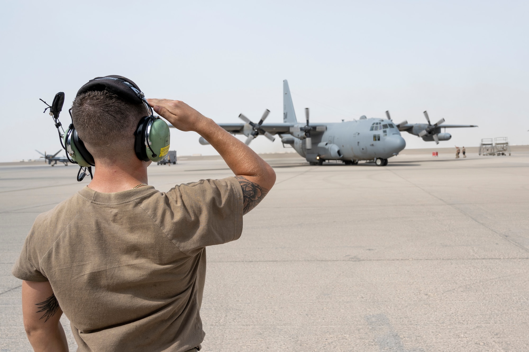 Airman saluting an EC-130h prior to takeoff