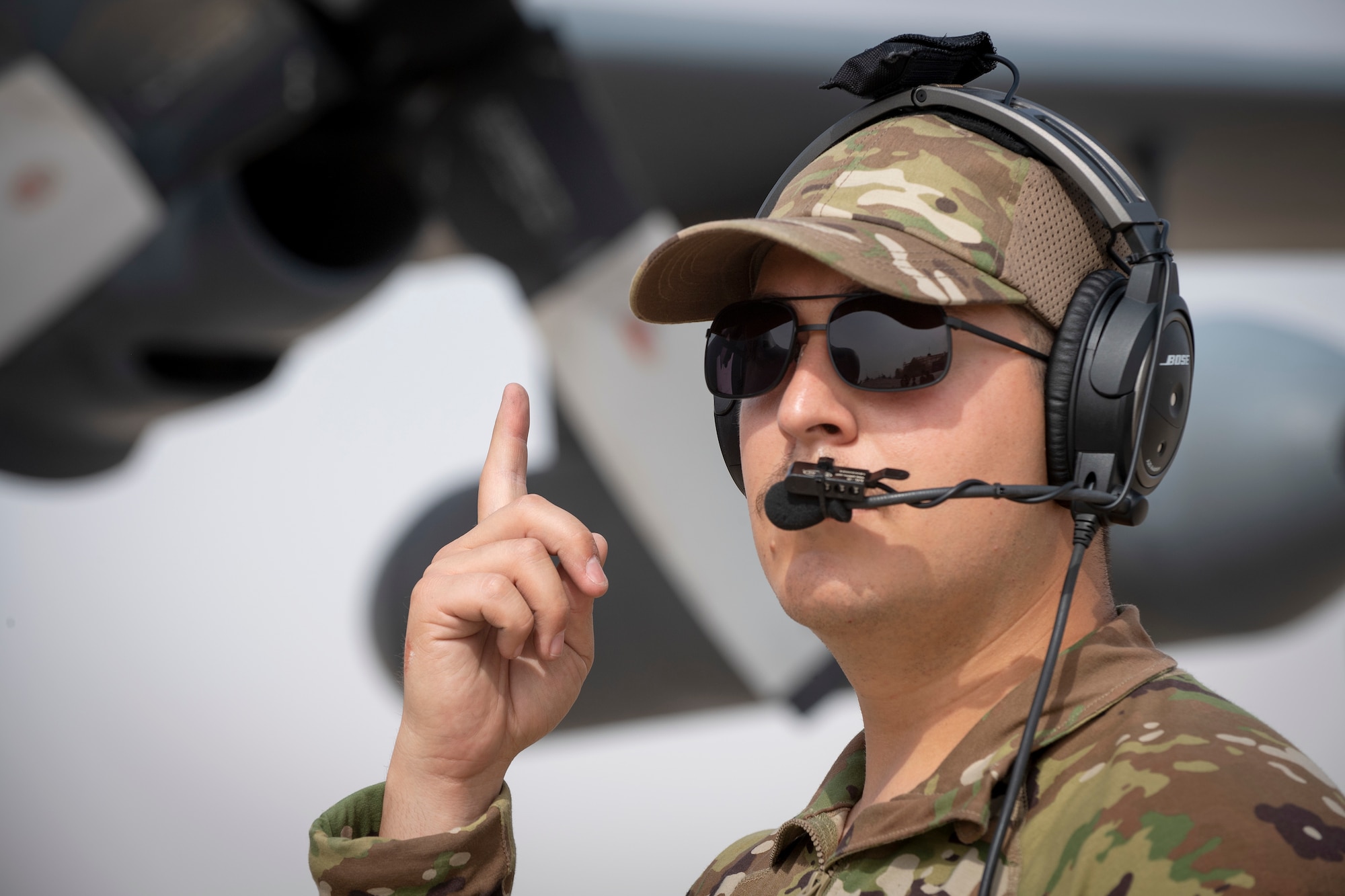 Airman signaling with index finger in front of aircraft