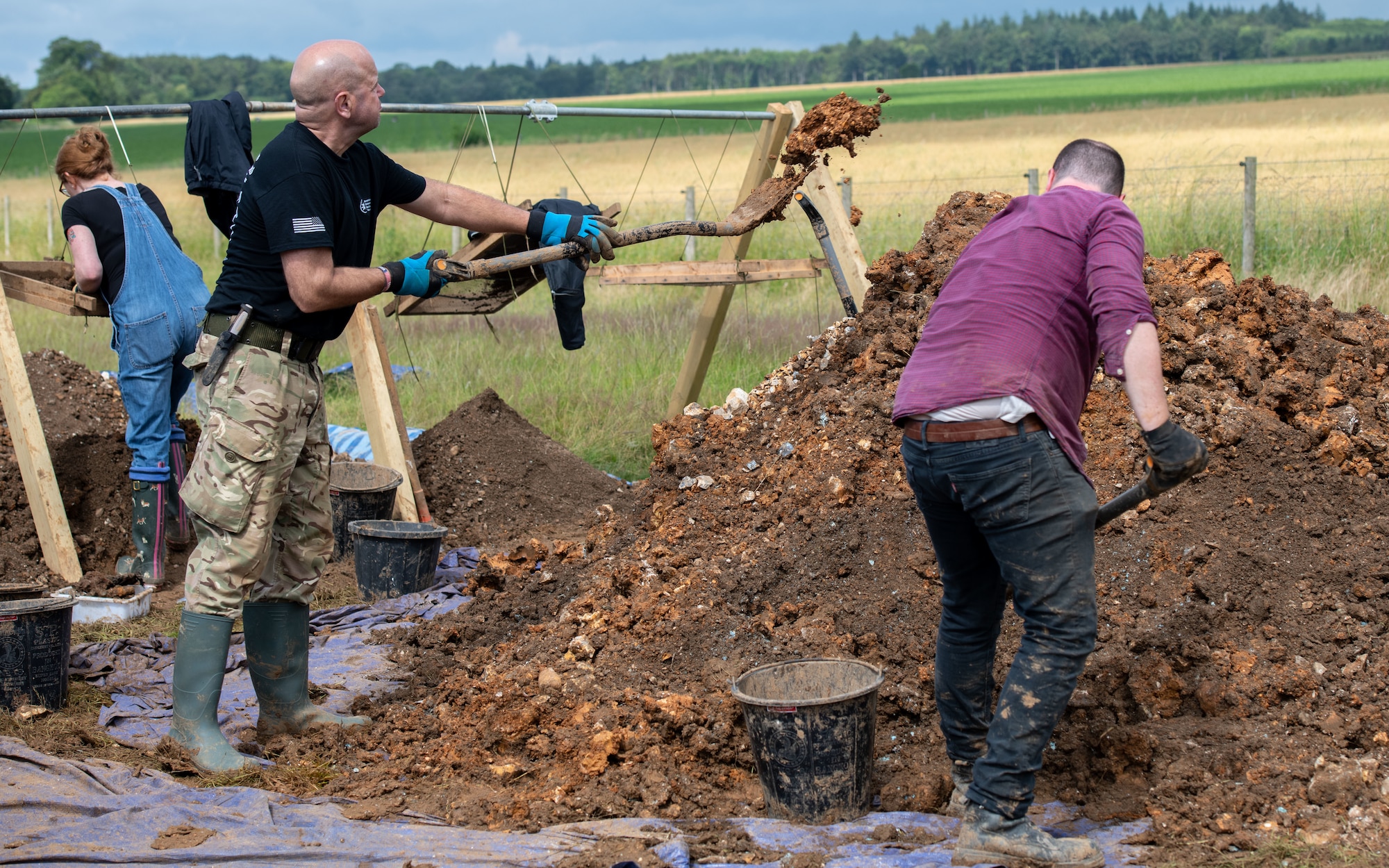 Volunteers with American Veterans Archaeological Recovery separate dirt and clay while trying to recover the remains of an aircrew from a World War II era B-24 Liberator crash site at Park Farm, Arundel, England, July 8, 2021. The team was comprised of around 20 volunteers from local universities, veterans from both United States and British armed forces, and active duty service members from RAF Lakenheath. (U.S. Air Force photo by Airman 1st Class Cedrique Oldaker)
