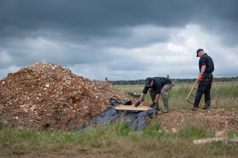 Gregory Ashcroft, squad lead for the American Veterans Archeological Recovery group, left, and Dr. Steven Humphreys, CEO of AVAR, search for remains of fallen service members during a B-24 Liberator excavation at Park Farm in Arundel, England, July 8, 2021. AVAR is conducting the dig in conjunction with the Defense POW/MIA Accounting Agency in an effort to recover those still missing in action. (U.S. Air Force photo by Senior Airman Koby I. Saunders)