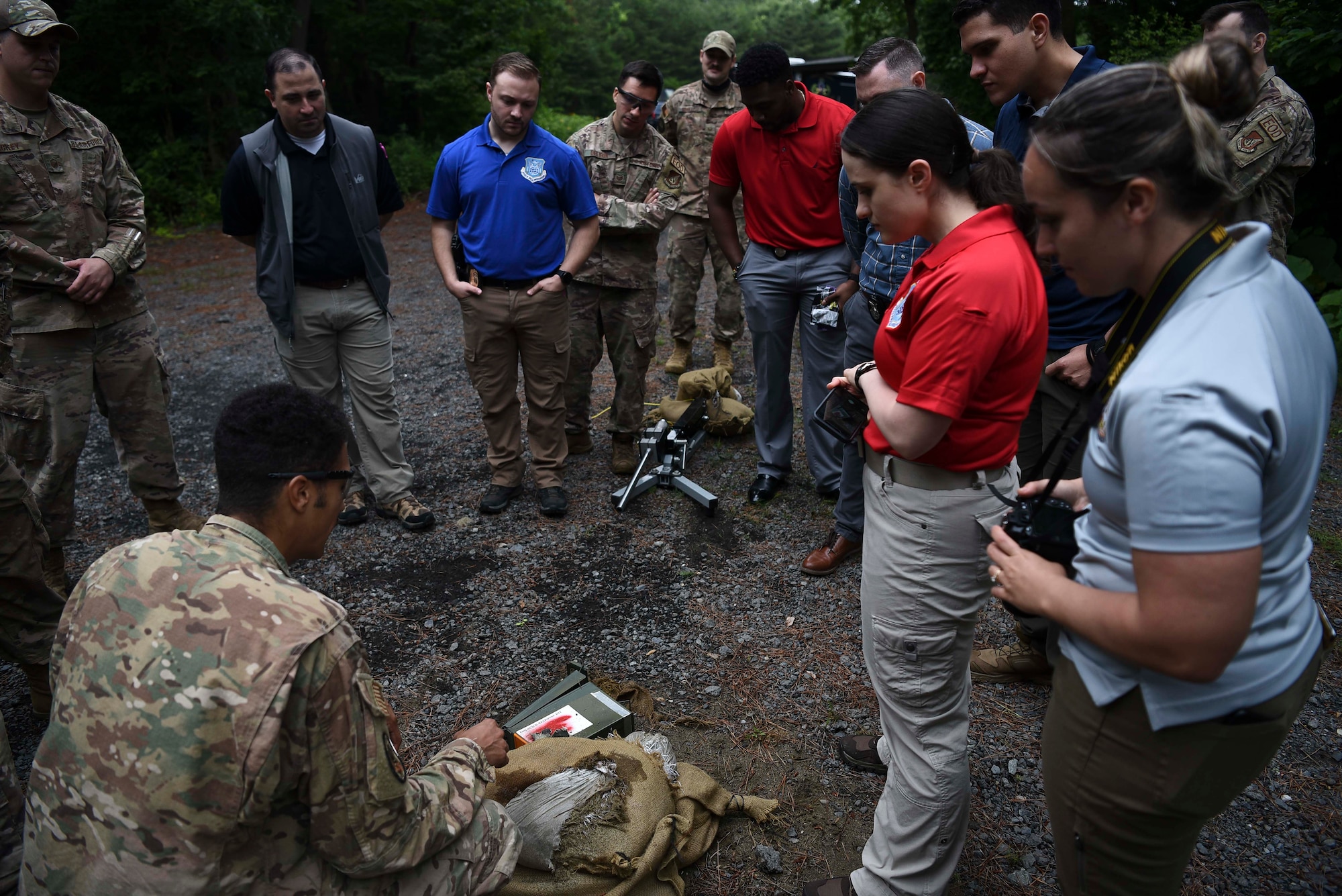 Military members stand around a prop bomb made with an ammo can that's been shot with an anti-bomb device.