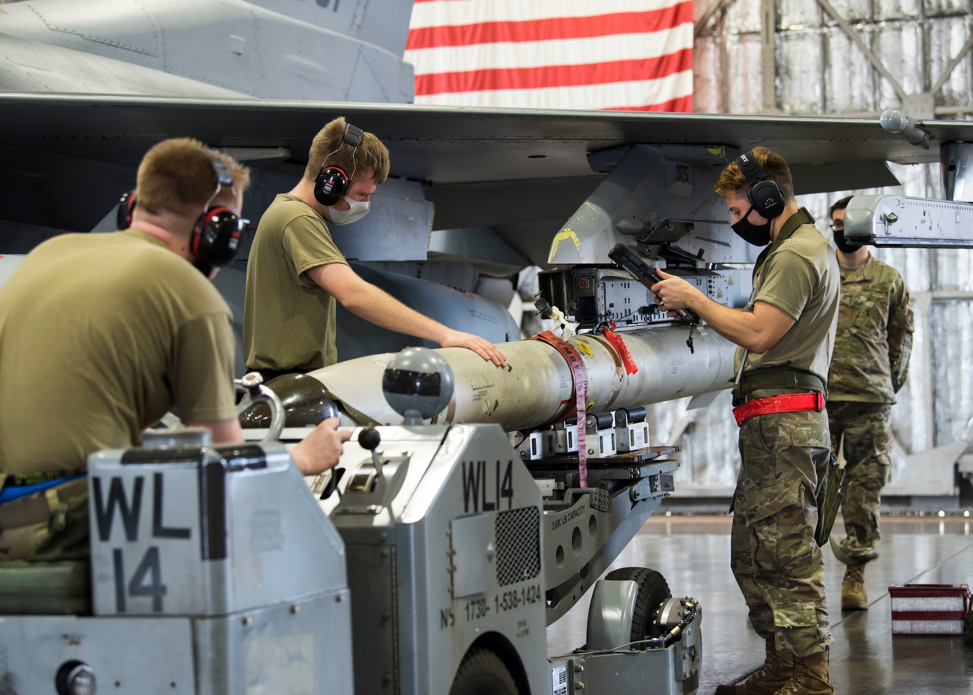 U.S. military members prepares munitions to be loaded and ready for an F-16.