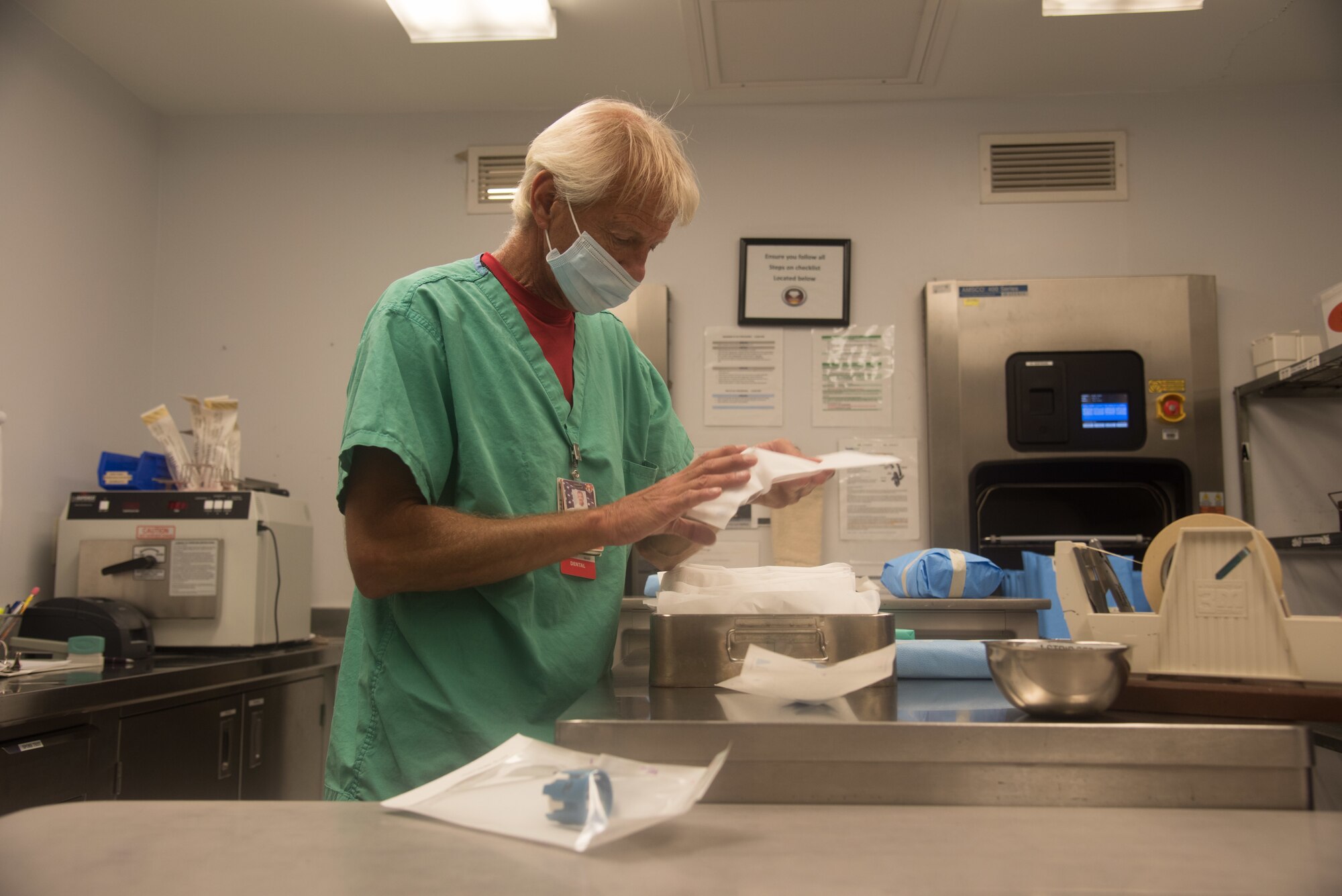 Man in scrubs sanitizes dental equipment